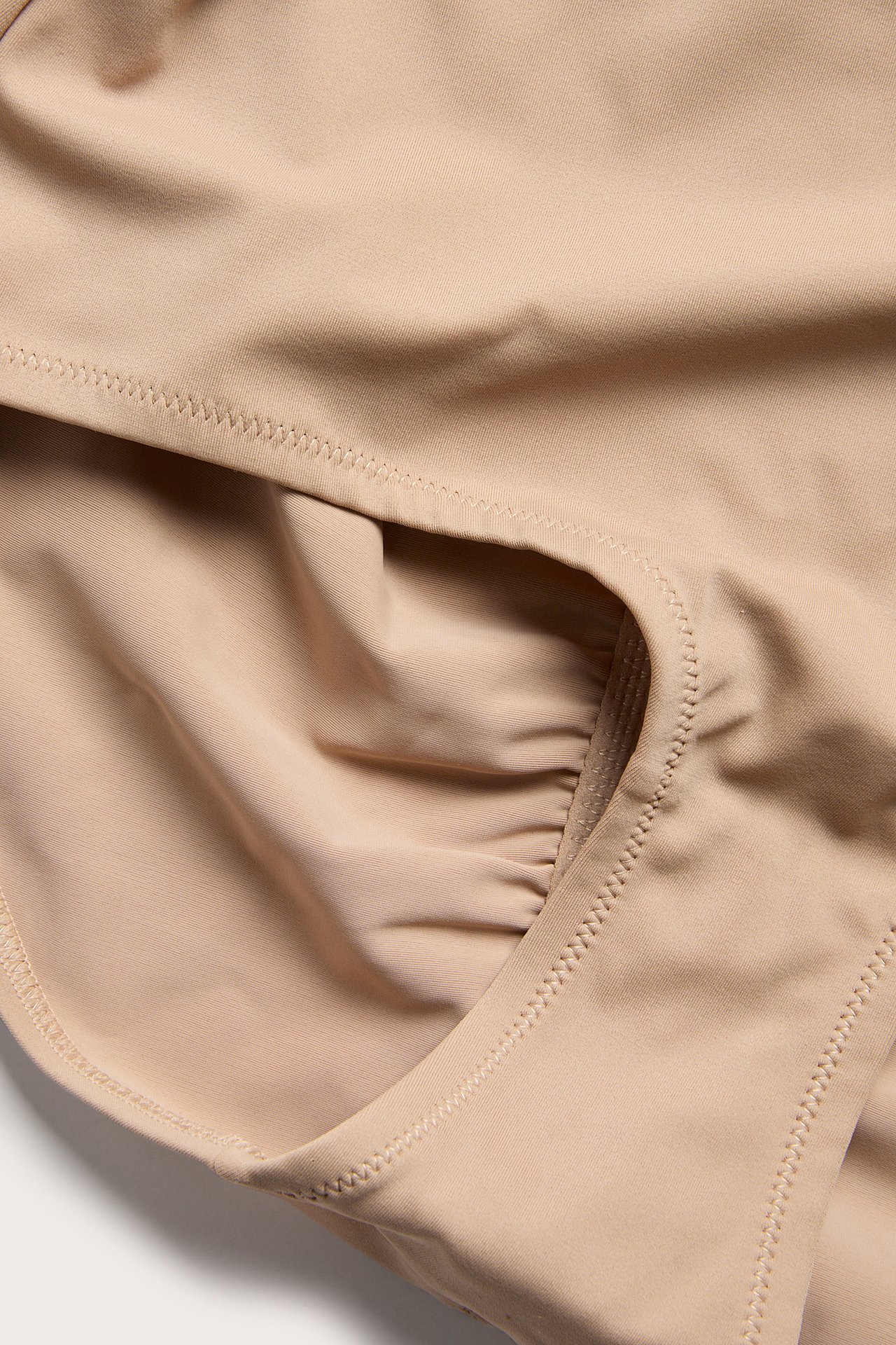 Lähikuva yksivärisistä ruskeista, korkeavyötäröisistä muotoilevista hipster-alushousuista, joissa on rypytys.