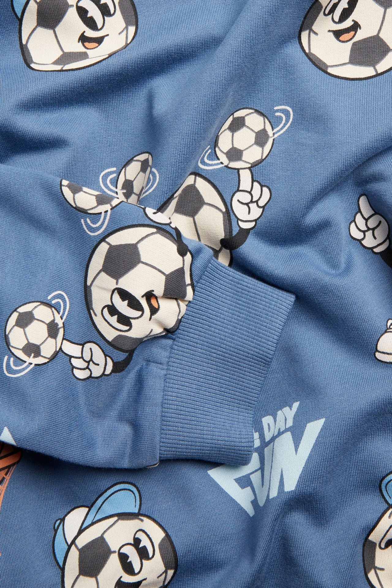 Zbliżenie na niebieską bawełnianą bluzę z piłkarskim wzorem i ściągaczem.