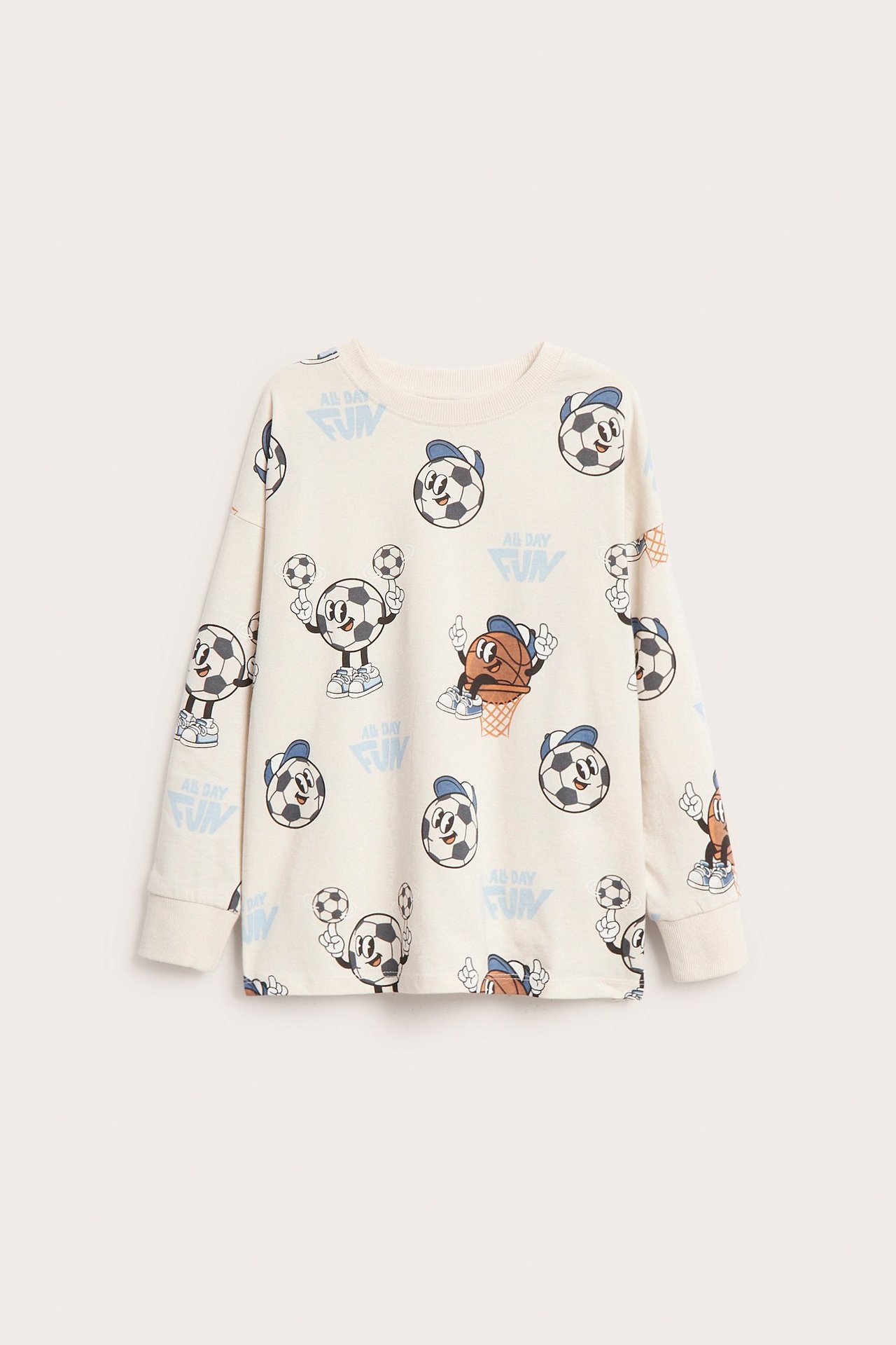 Framifrån: Långärmad t-shirt i ljusbeige bomull för barn med tecknat sportbollsmönster.