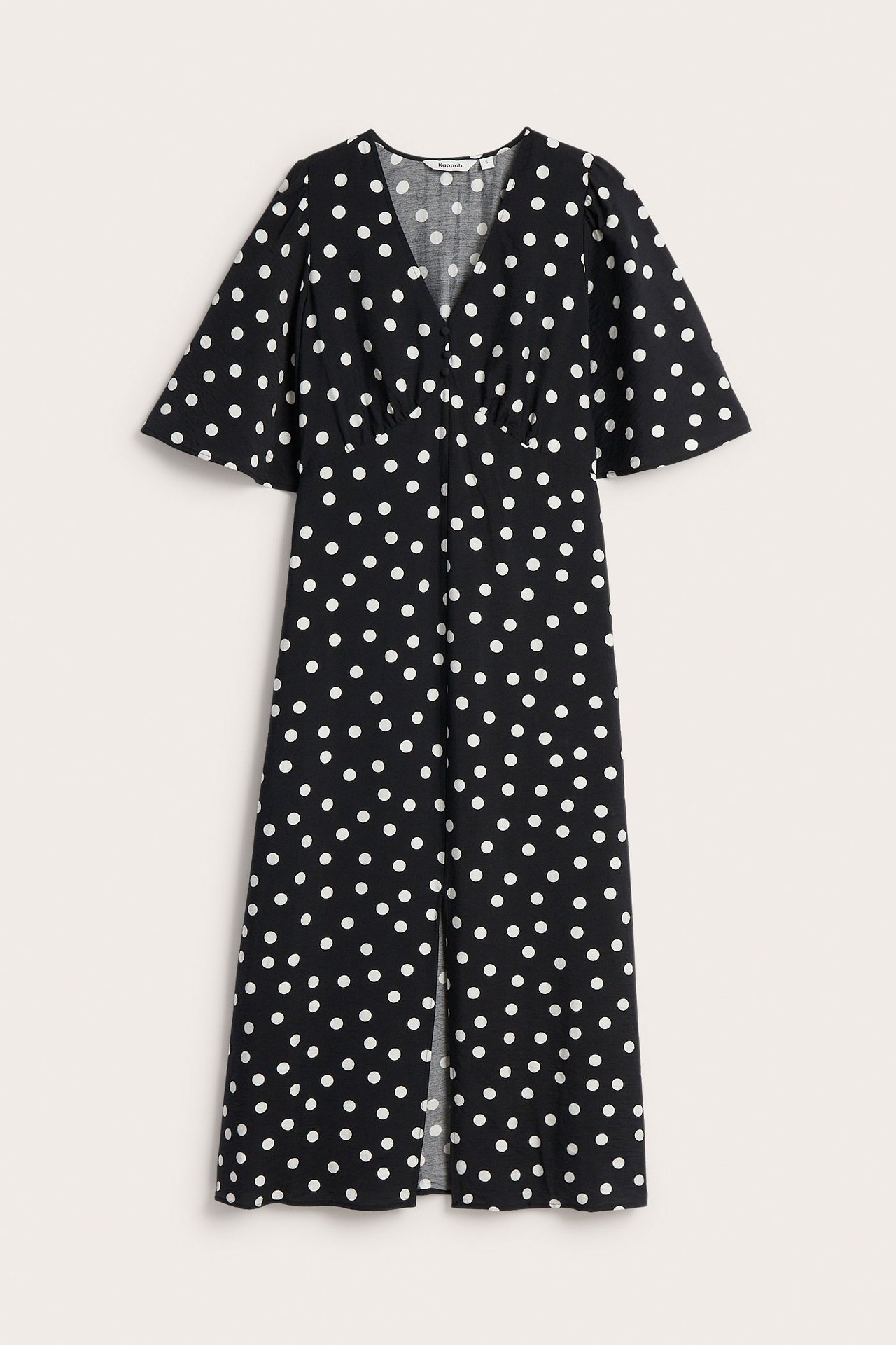 Edestä: Musta pilkullinen midimekko, jossa valkoisia palloja, V-pääntie, napit edessä, röyhelöhihat ja etuhalkio.