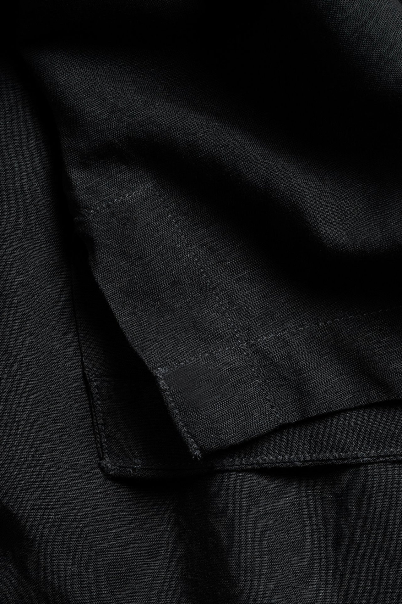 Närbild av en svart linneblandningsskjorta, som visar synliga sömdetaljer på tyget.