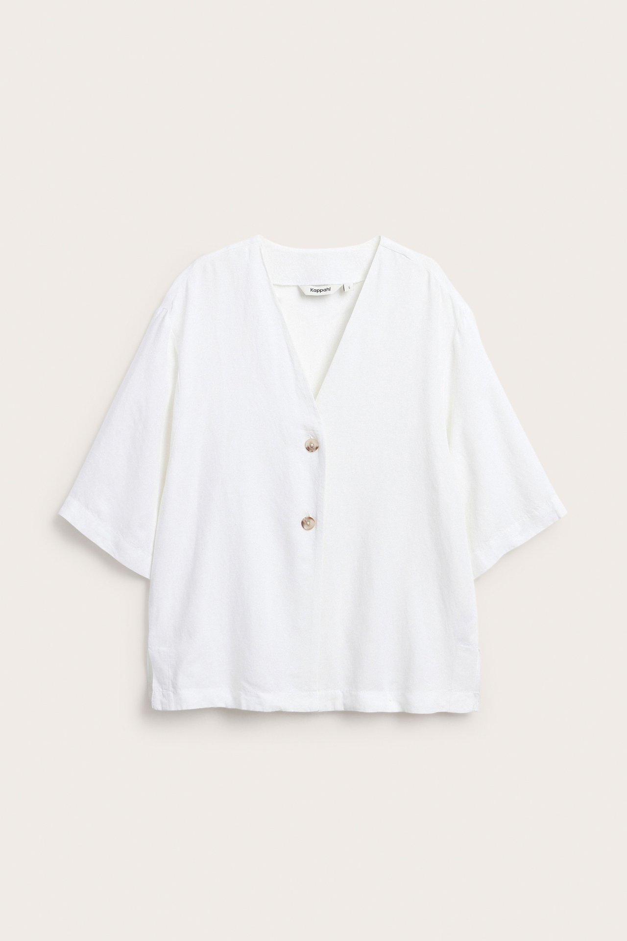 Framifrån, vit kortärmad skjorta i linnemix med V-ringning och två ljusbruna knappar framtill.