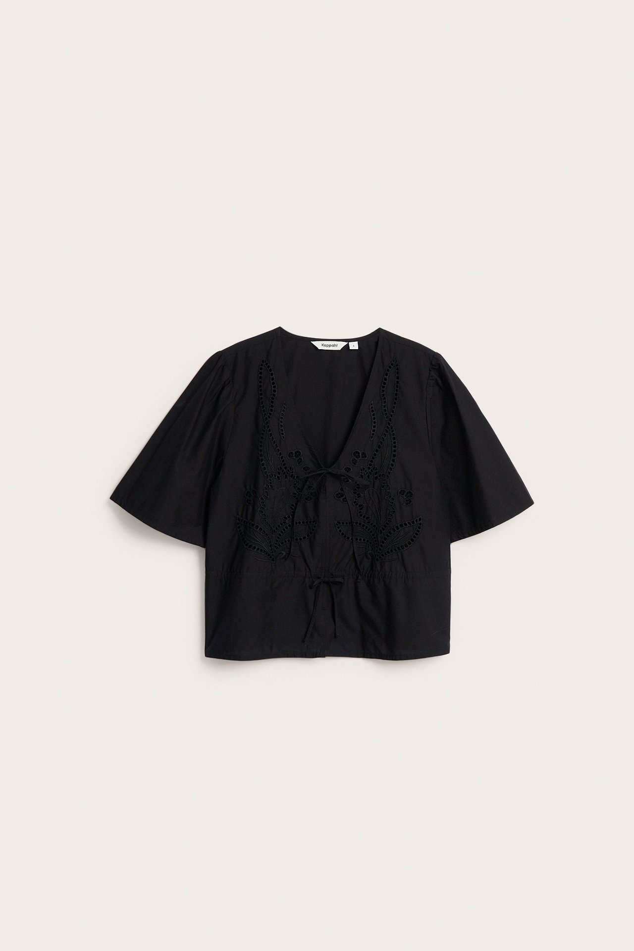 Edestä näkymä mustasta puuvillapopliinipuserosta, jossa kirjailu, V-pääntie, lyhyet hihat ja vyötärönyöri.