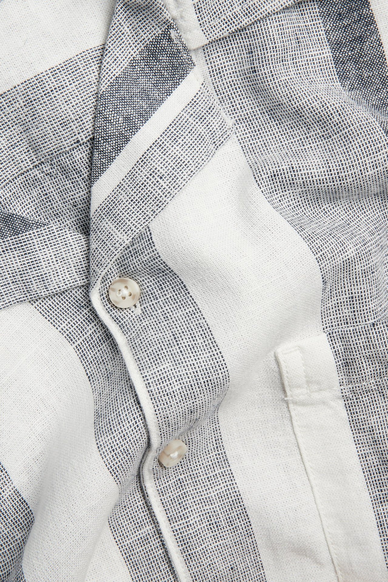 Lähikuva miesten tummansinisestä ja valkoisesta raidallisesta pellava-viskoosipaidasta napeilla ja taskulla.