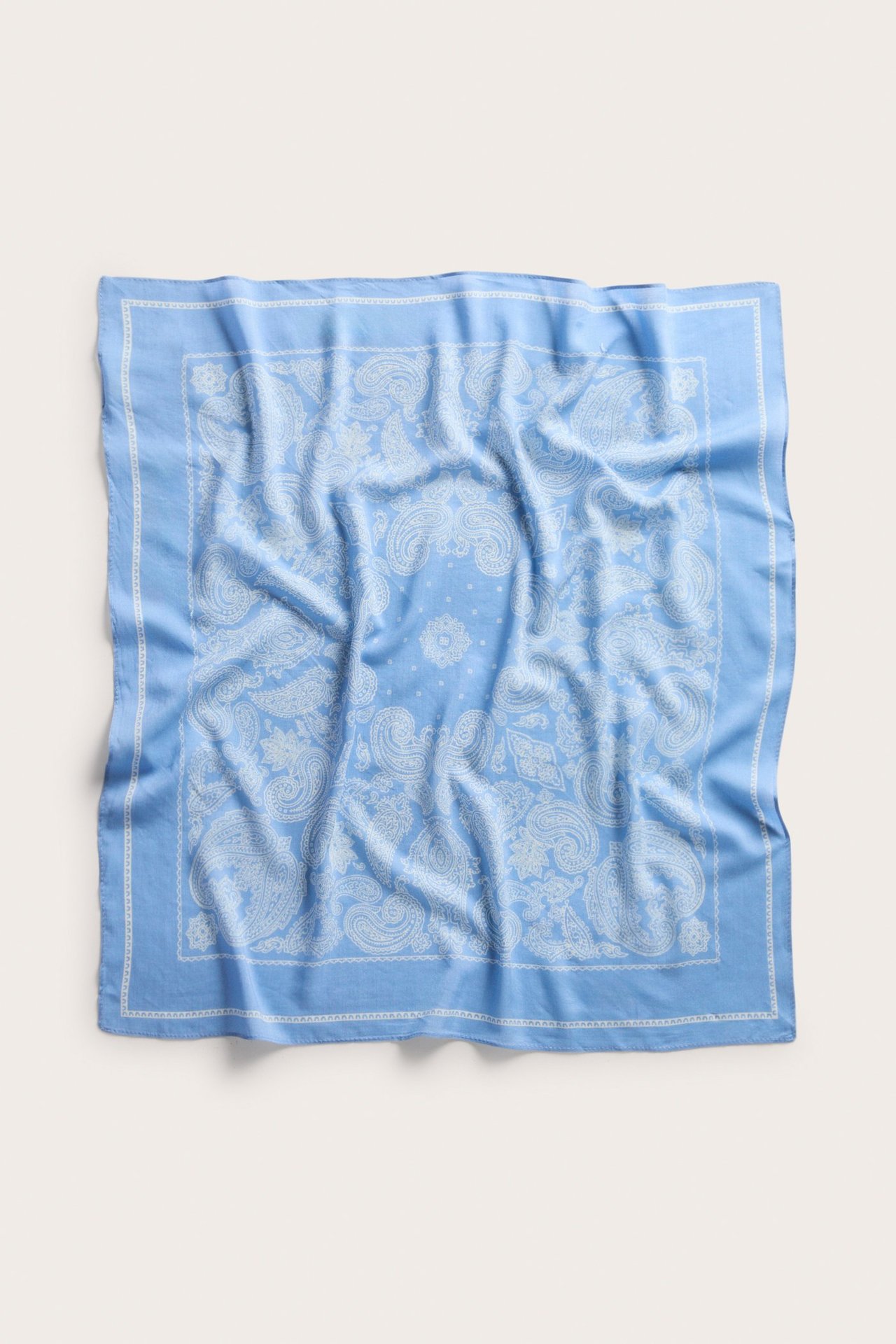 Topputsikt over et lyseblått kvadratisk viskoseblandet skjerf med hvitt paisleymønster.