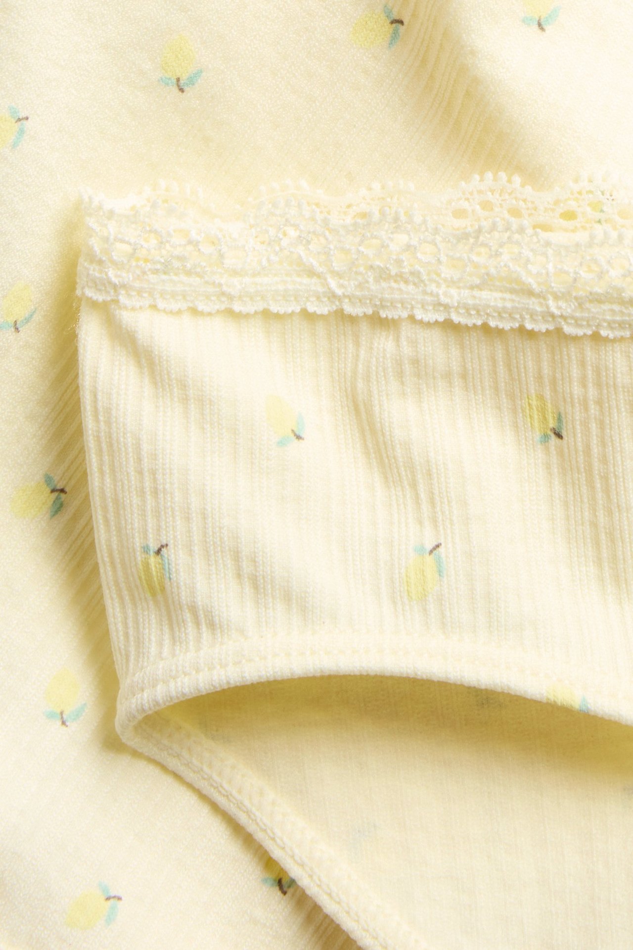 Zbliżenie jasnych żółtych bezszwowych fig z delikatnym wzorem w cytryny i koronkową lamówką.