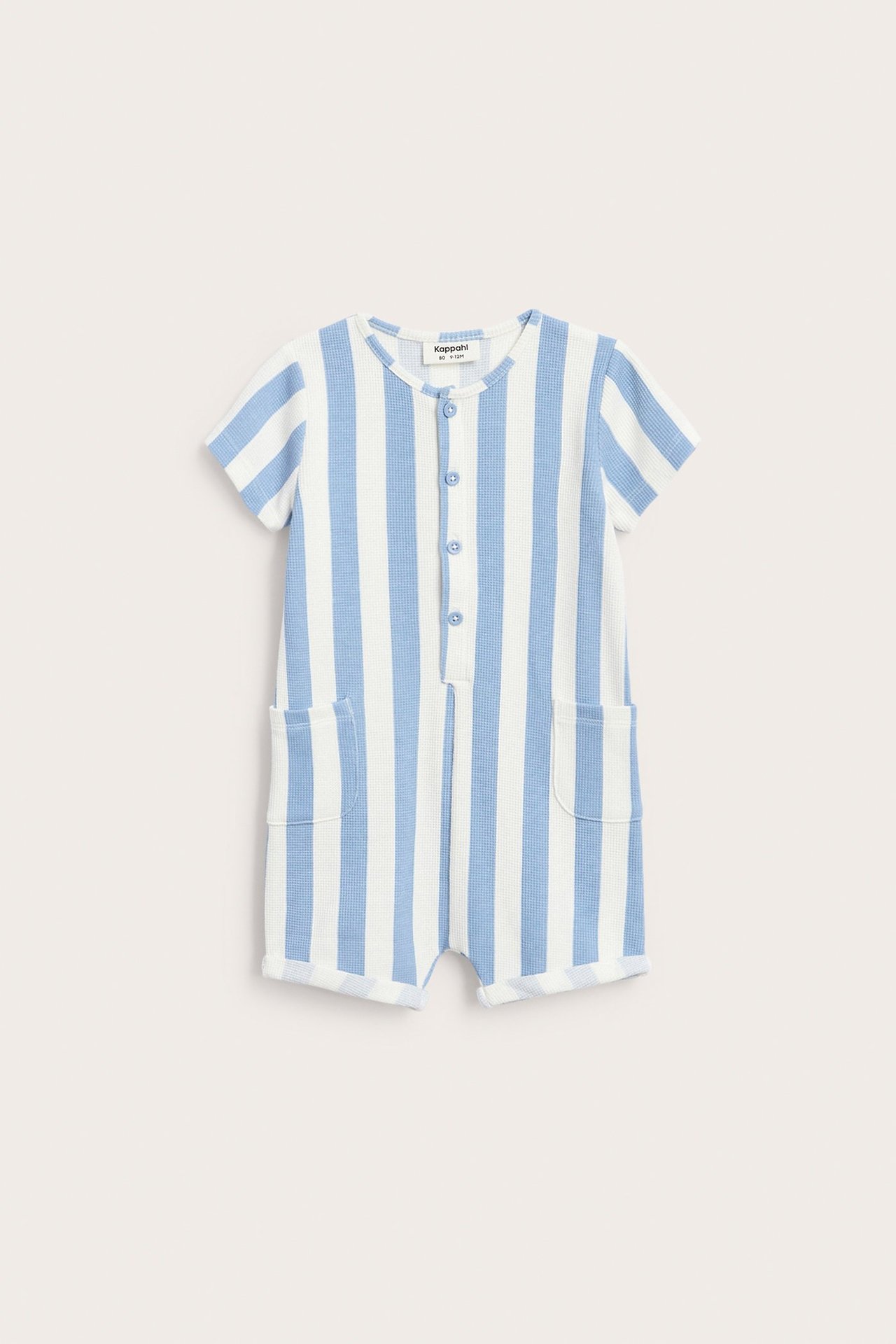 Edestä: Raidallinen vaaleansinivalkoinen vohvelikankainen vauvan romper etunapeilla ja kahdella taskulla.