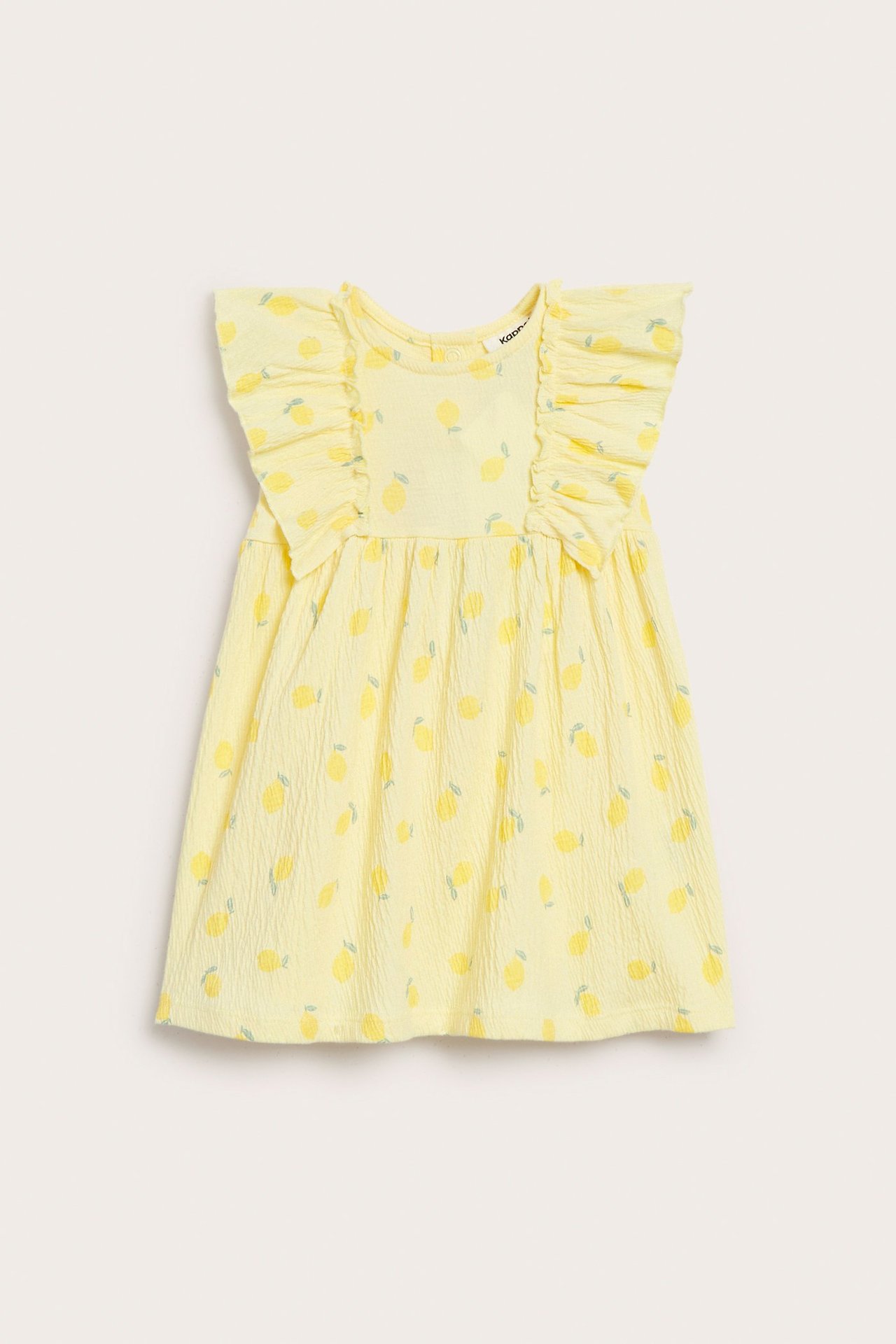 Edestä: vaaleankeltainen, sitruunakuvioinen vauvan kreppijerseymekko olkarypyillä.