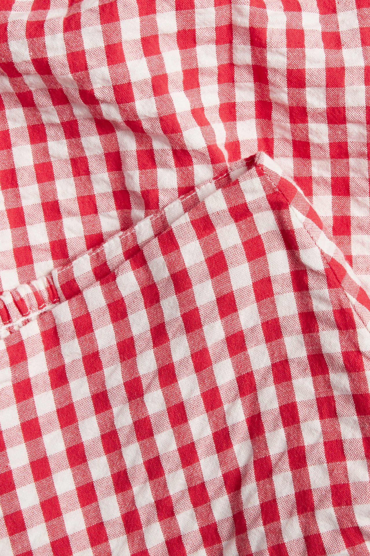 Zbliżenie czerwono-białego, kraciastego materiału spódnicy seersucker z lekkimi marszczeniami.