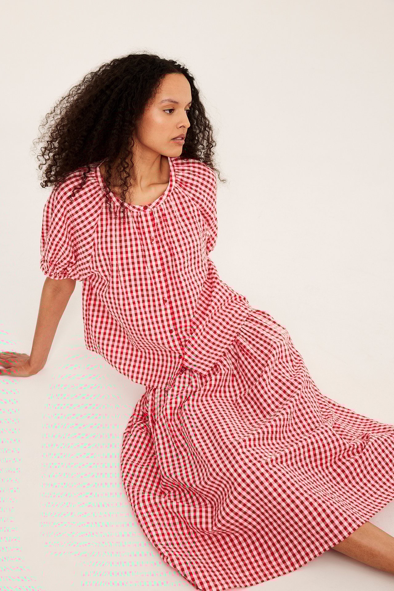 Kvinna i en röd- och vitrutig bäckebölja midikjol och matchande kortärmad topp.