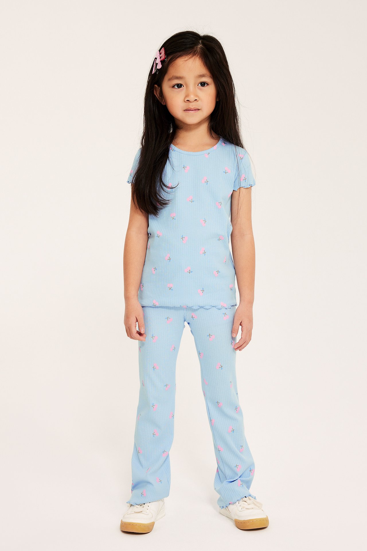 Frontvisning av et barn i lyseblå ribbestrikkede flare-leggings med kirsebærtrykk og en matchende t-skjorte.