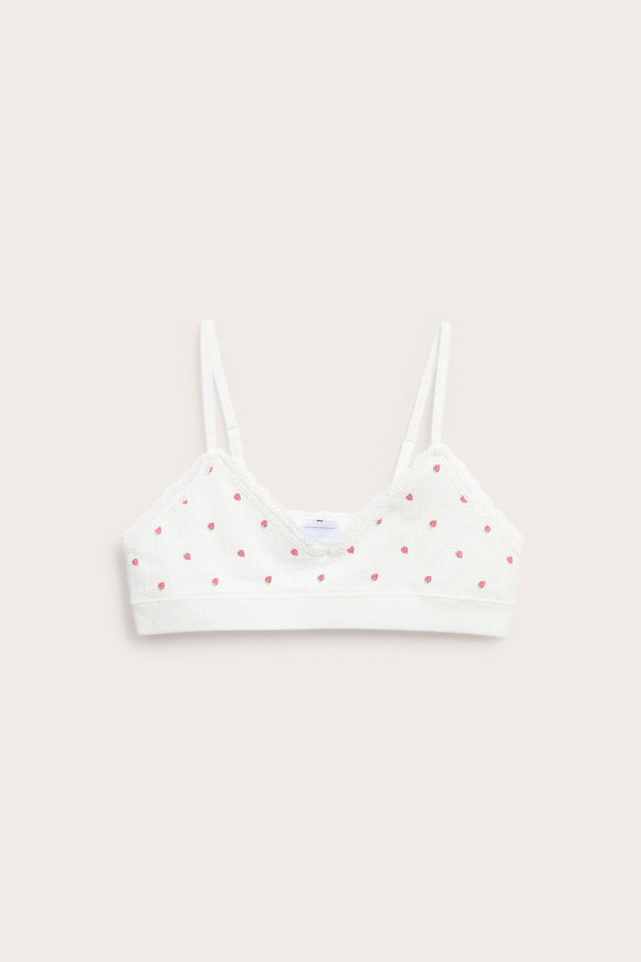 Widok z przodu: kremowy bezszwowy top z dekoltem V, koronką i wzorem w truskawki.