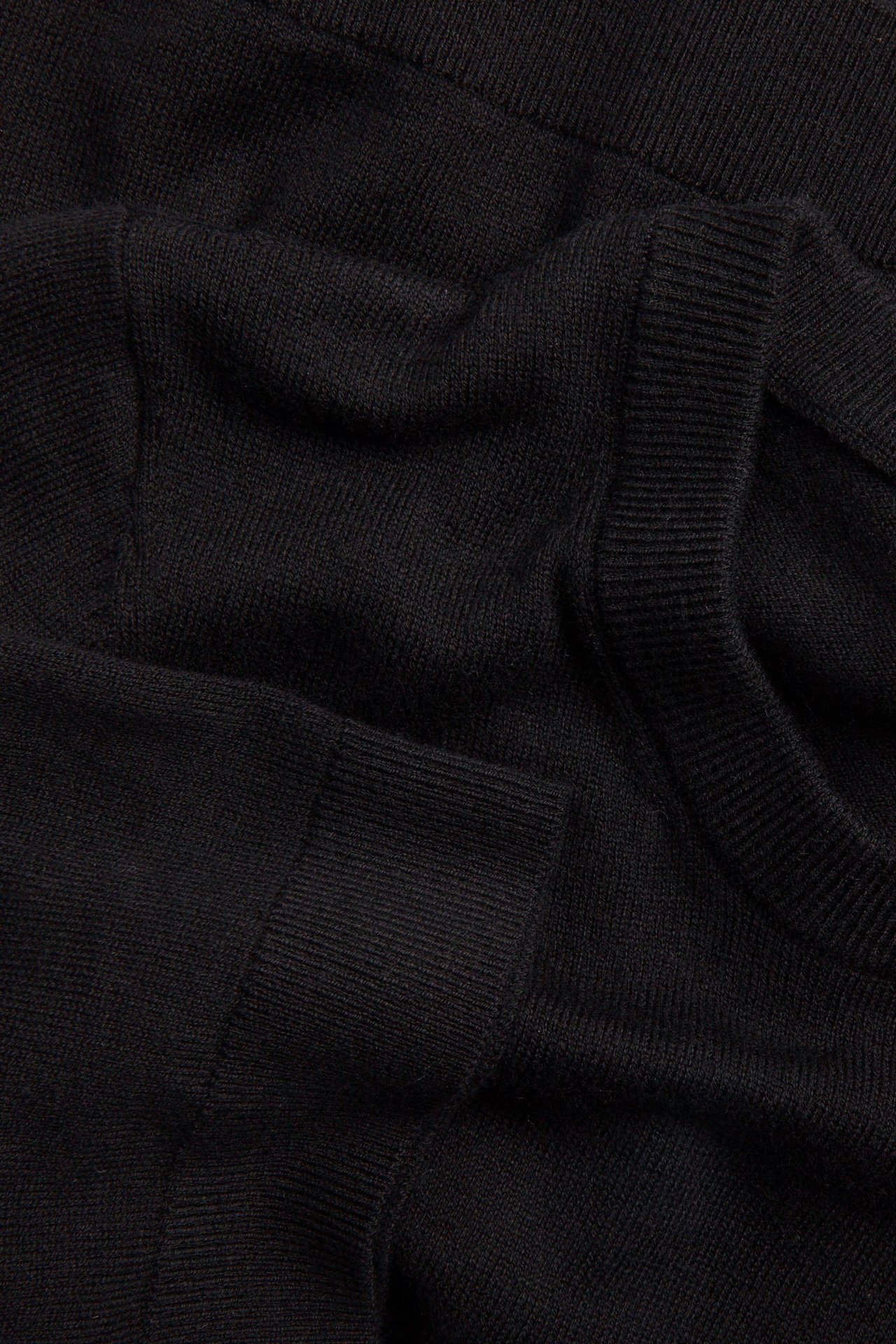 Zbliżenie czarnego, drobno dzianego swetra z mieszanki wełny, z prążkowanym kołnierzem i mankietem.
