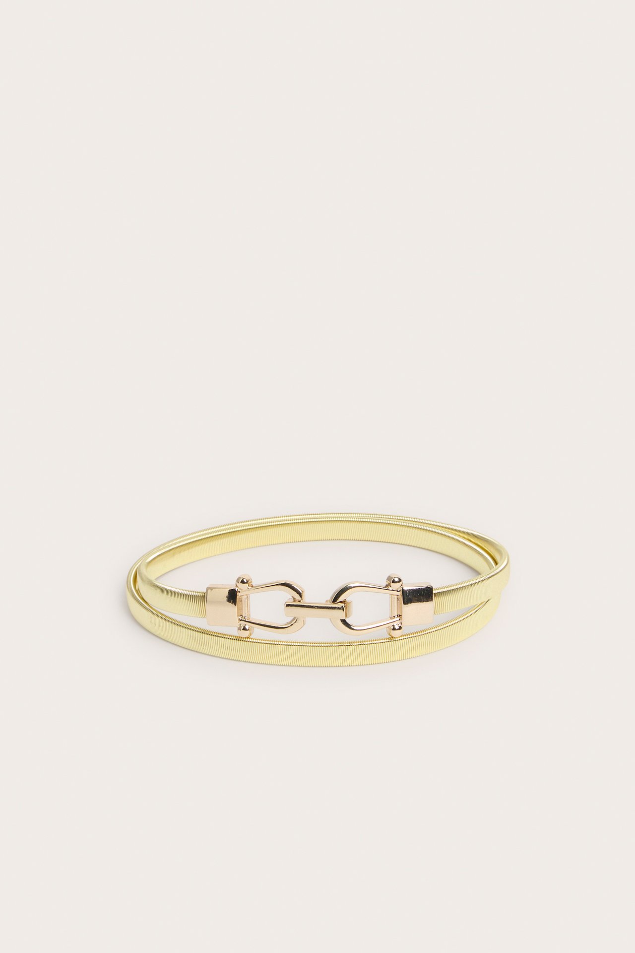 Framifrån, ett guldfärgat elastiskt metallbälte med dekorativt guldfärgat spänne.