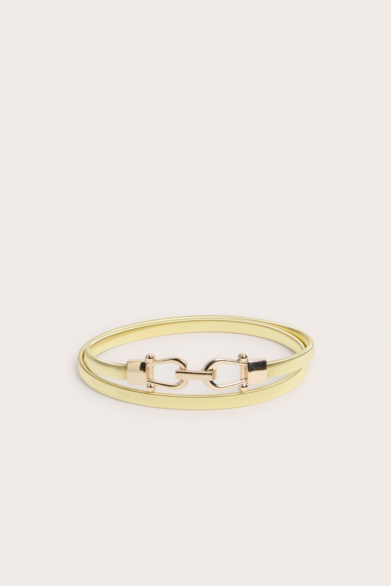 Framifrån, ett guldfärgat elastiskt metallbälte med dekorativt guldfärgat spänne.