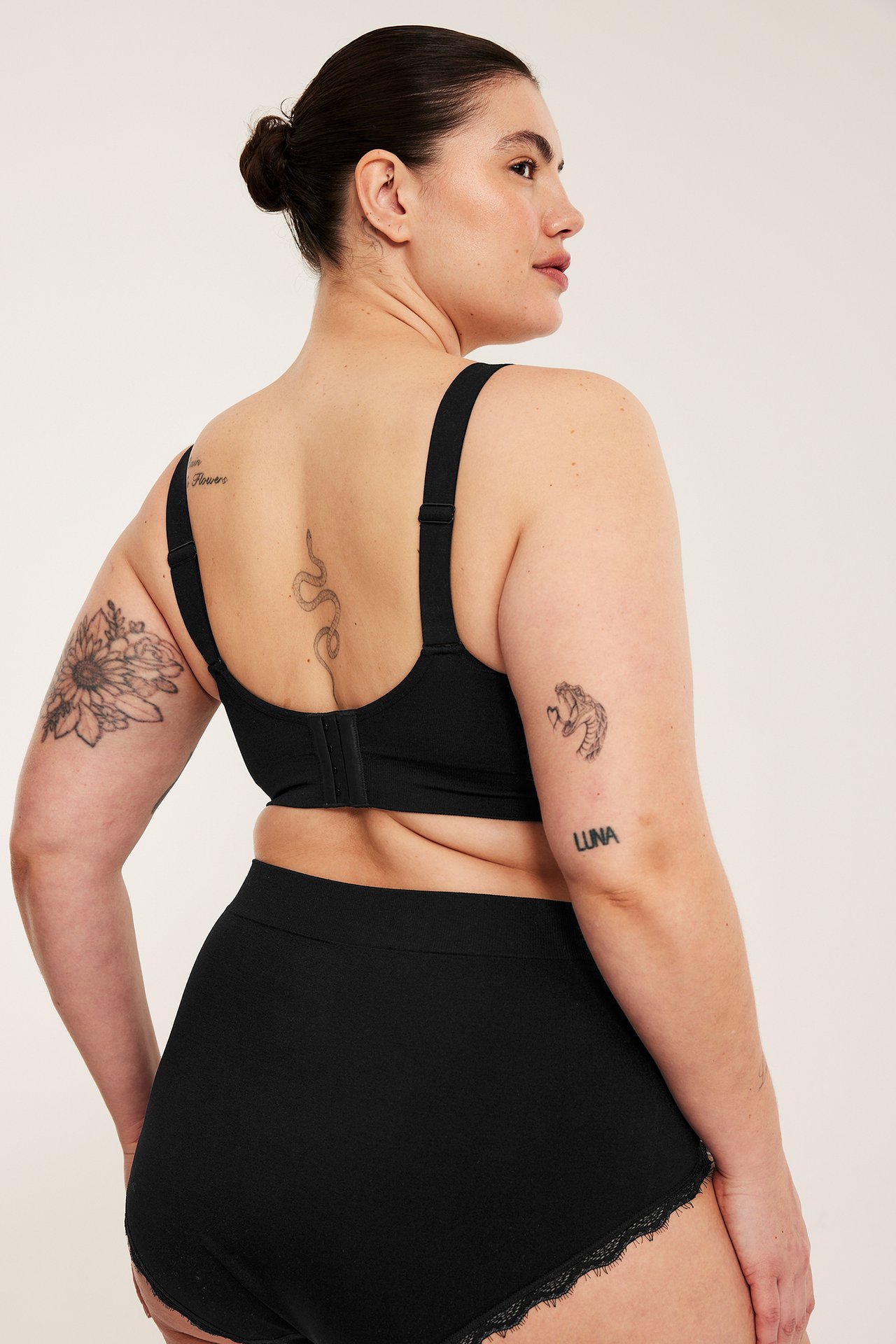 Widok z tyłu: kobieta w czarnym bezszwowym biustonoszu bez fiszbin i czarnych majtkach z koronkowym wykończeniem.