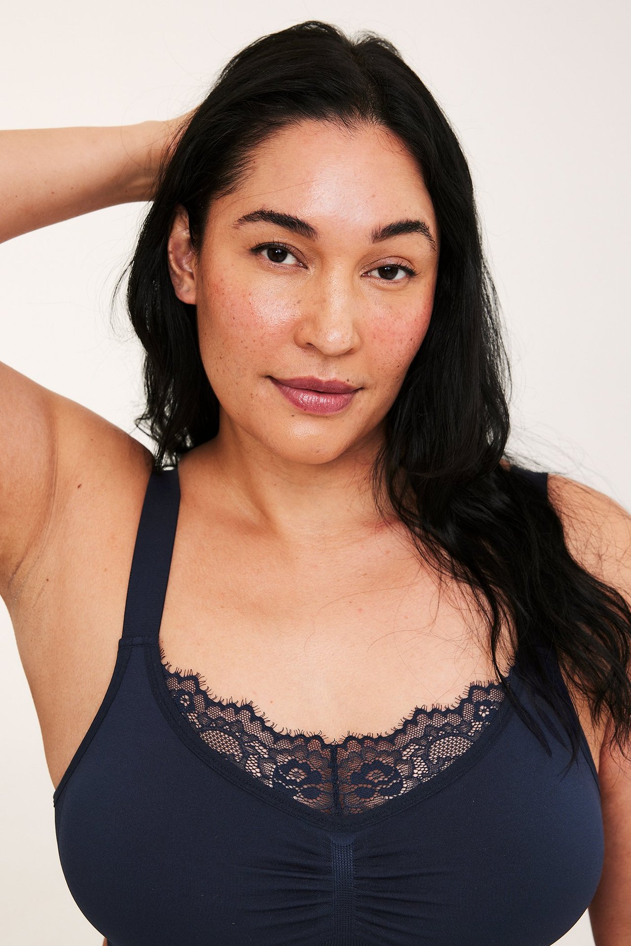 Nærbilde av kvinne i mørkeblå sømløs bøylefri BH med blondedetaljer og rynker foran.