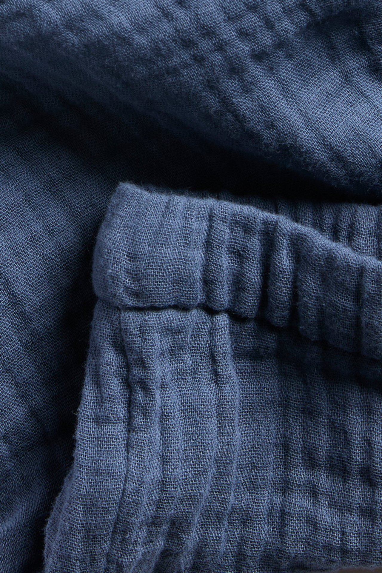 Nærbilde av blå vevde muslinsorts med elastisk linning.