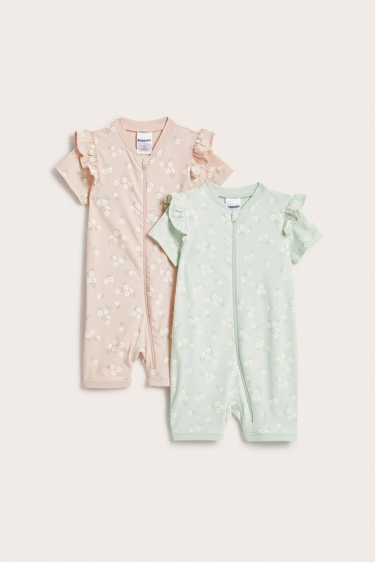 Frontvy av två kortärmade babyrompers: en rosa, en ljusgrön, båda med blommigt tryck och axelfrillor.