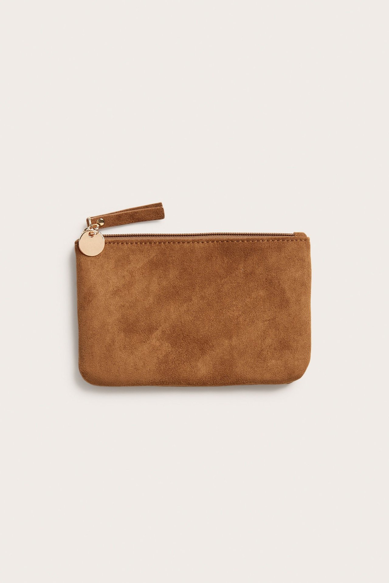 Edestäpäin kuvattu ruskea mokkajäljitelmäpussi, jossa vetoketju ja pieni kultainen riipus.