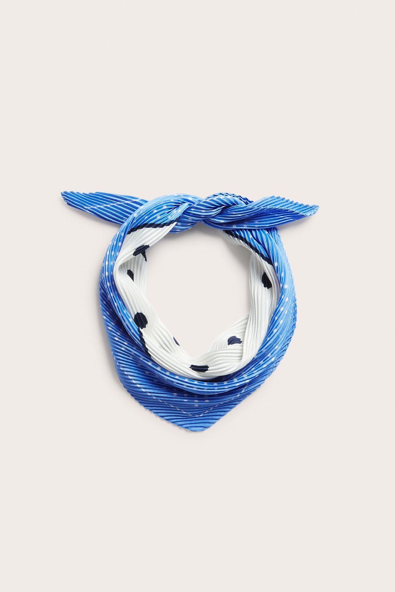 Nærbilde av et plissert blått og hvitt mønstret polyester skjerf, knyttet.