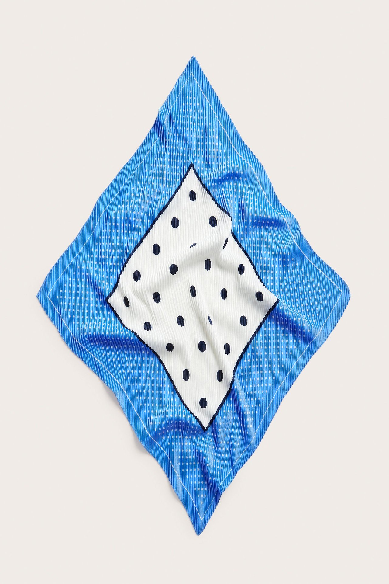 Ylhäältä näkymä: Laskostettu sininen polyesterihuivi valkoisilla pisteillä, keskiössä valkoinen timantti mustilla pisteillä.