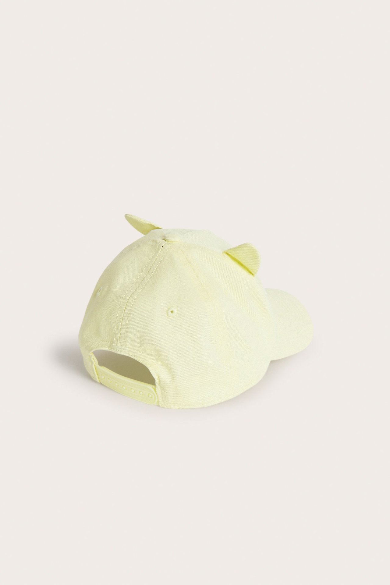 Baksidan av en ljusgul barnkeps med små öron och justerbart snapback-spänne.