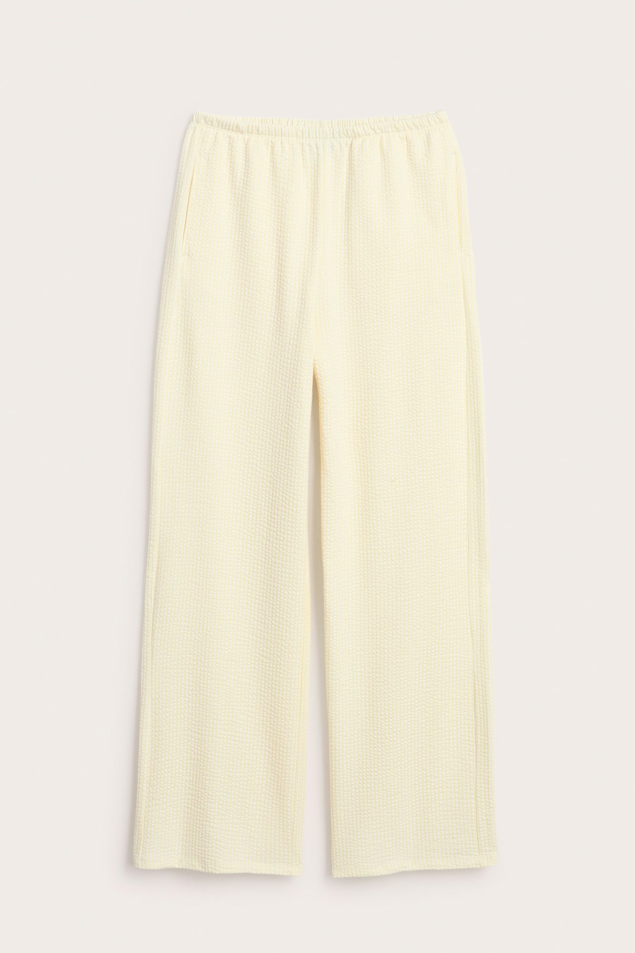Framsida ljusgula pyjamasbyxor med vid passform, bäckebölja-struktur, resår i midjan och sidfickor.