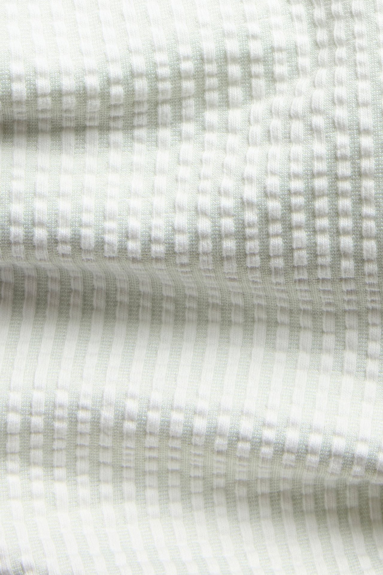 Närbild av ljusgröna och vita randiga pyjamasbyxor i bäckebölja-textur.