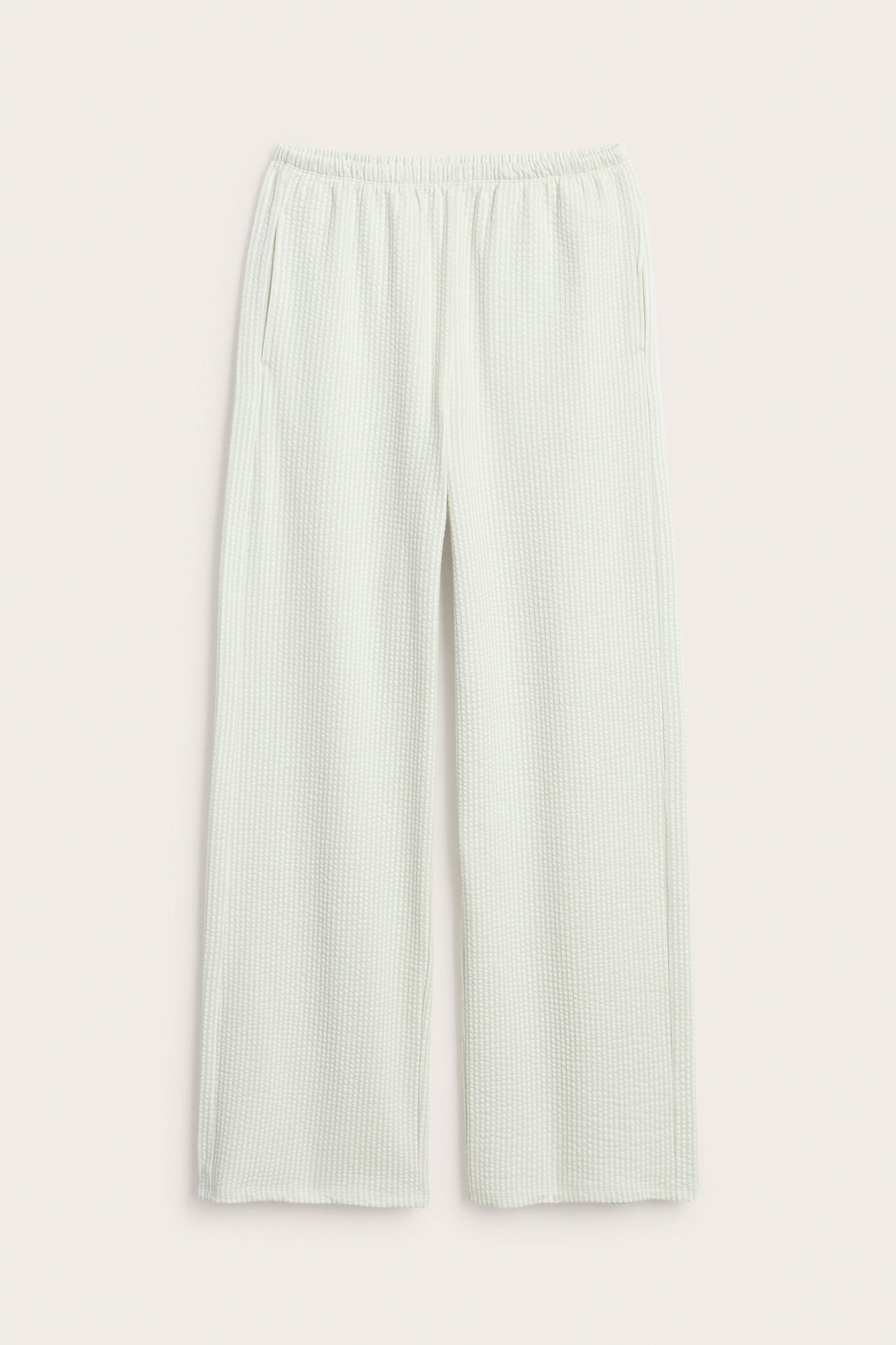 Widok z przodu: jasnozielone piżamowe spodnie w paski, z elastyczną talią i bocznymi kieszeniami.