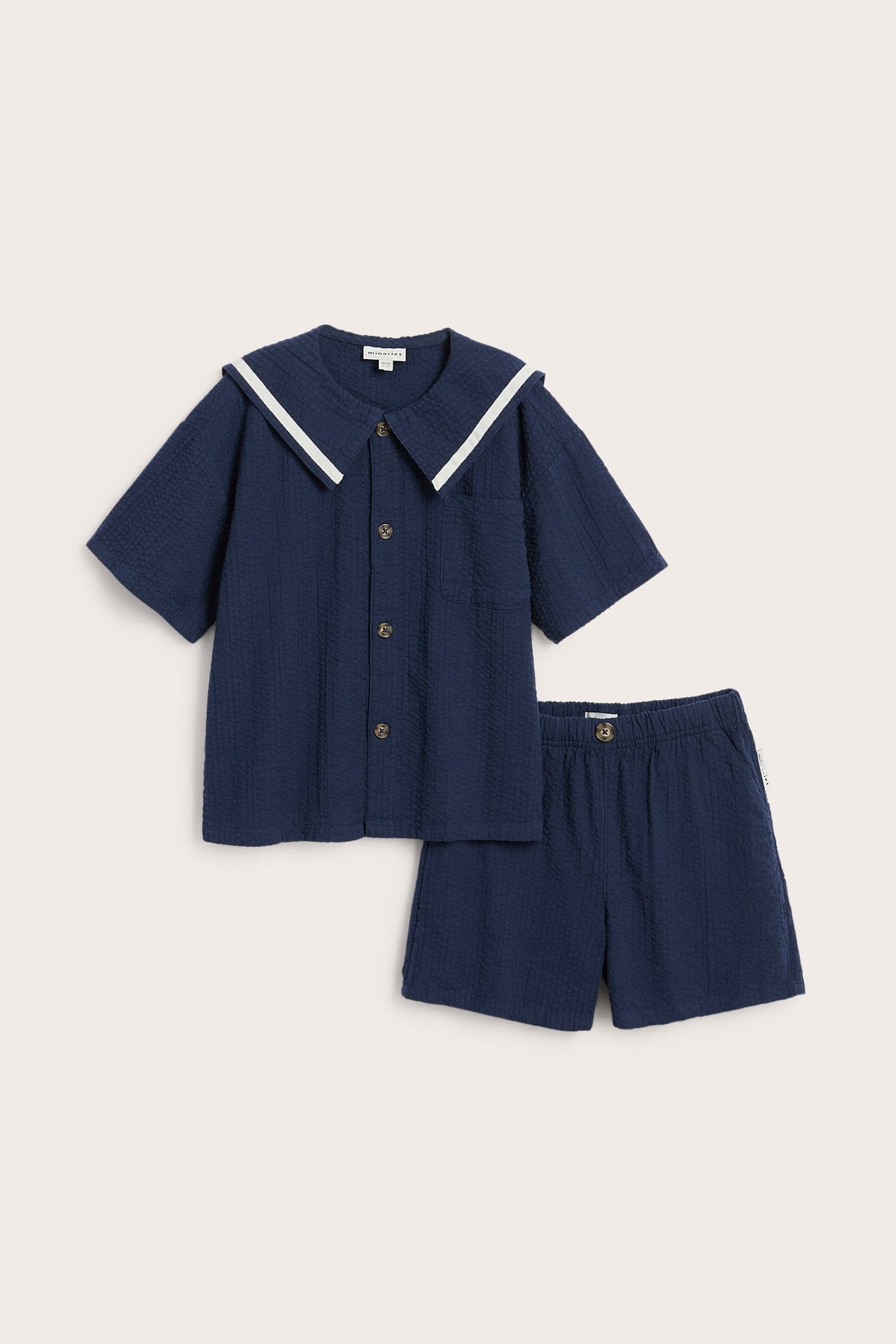 Framifrån: Blått seer-sucker-set för barn, en skjorta med vit sjömanskrage och matchande shorts.