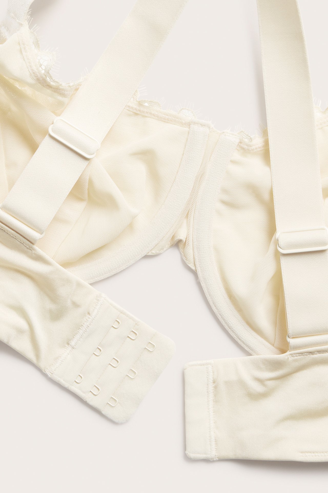 Nærbilde av en offwhite blonde-BH med spiler, justerbare stropper og hektelukking.