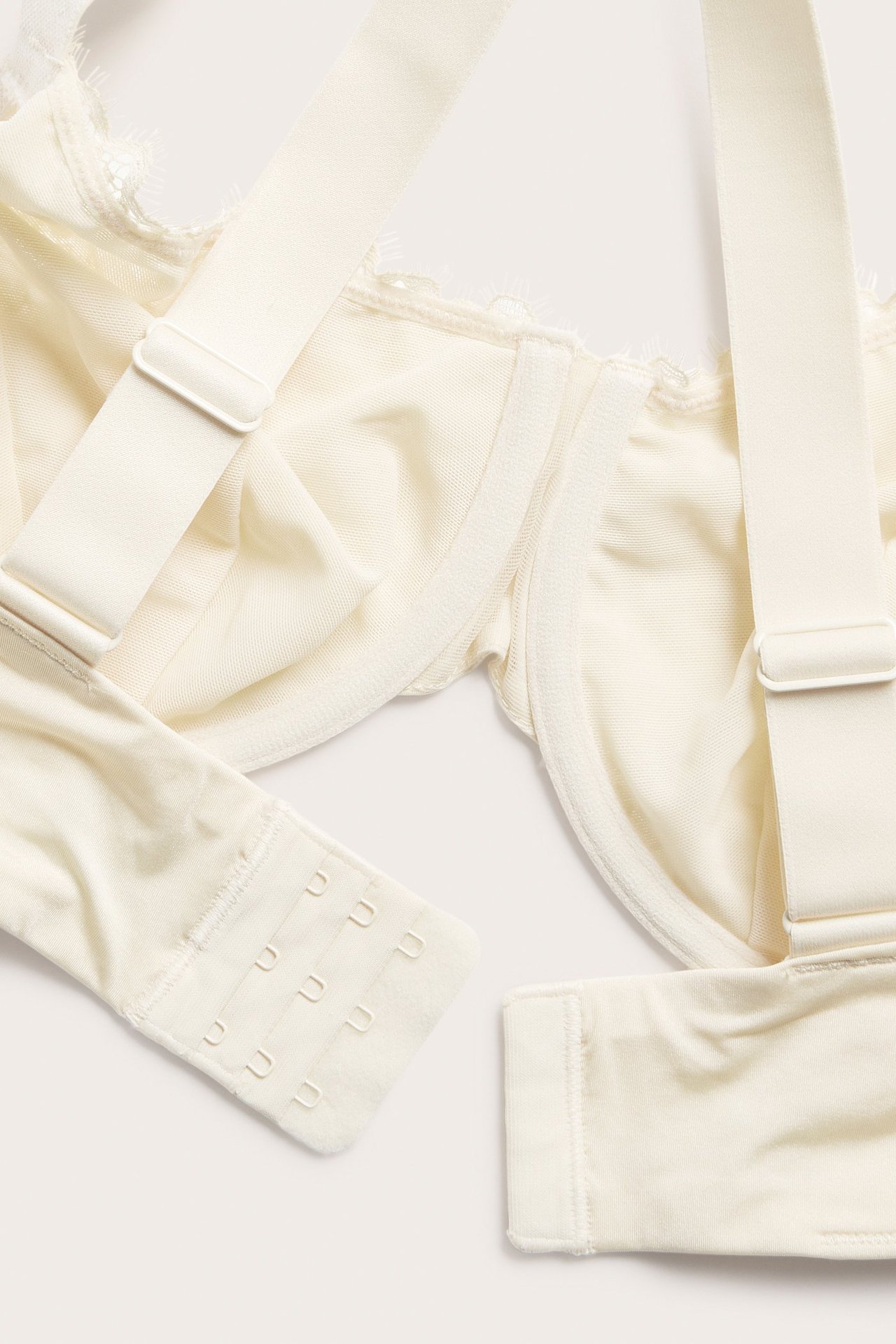 Nærbilde av en offwhite blonde-BH med spiler, justerbare stropper og hektelukking.