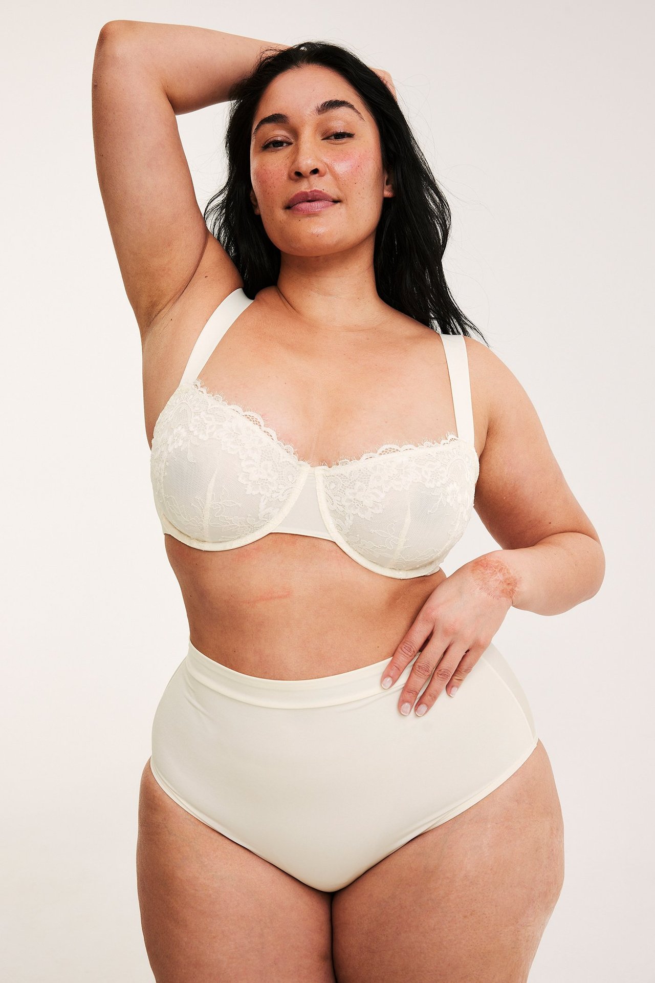 Framifrån, kvinna i offwhite spetsbygel-bh och matchande högmidjade trosor.