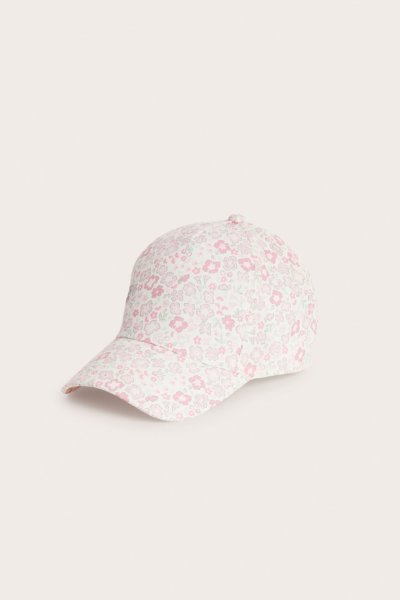 Snedvy av en benvit bomullstwillkeps med rosa och grönt blommigt mönster.