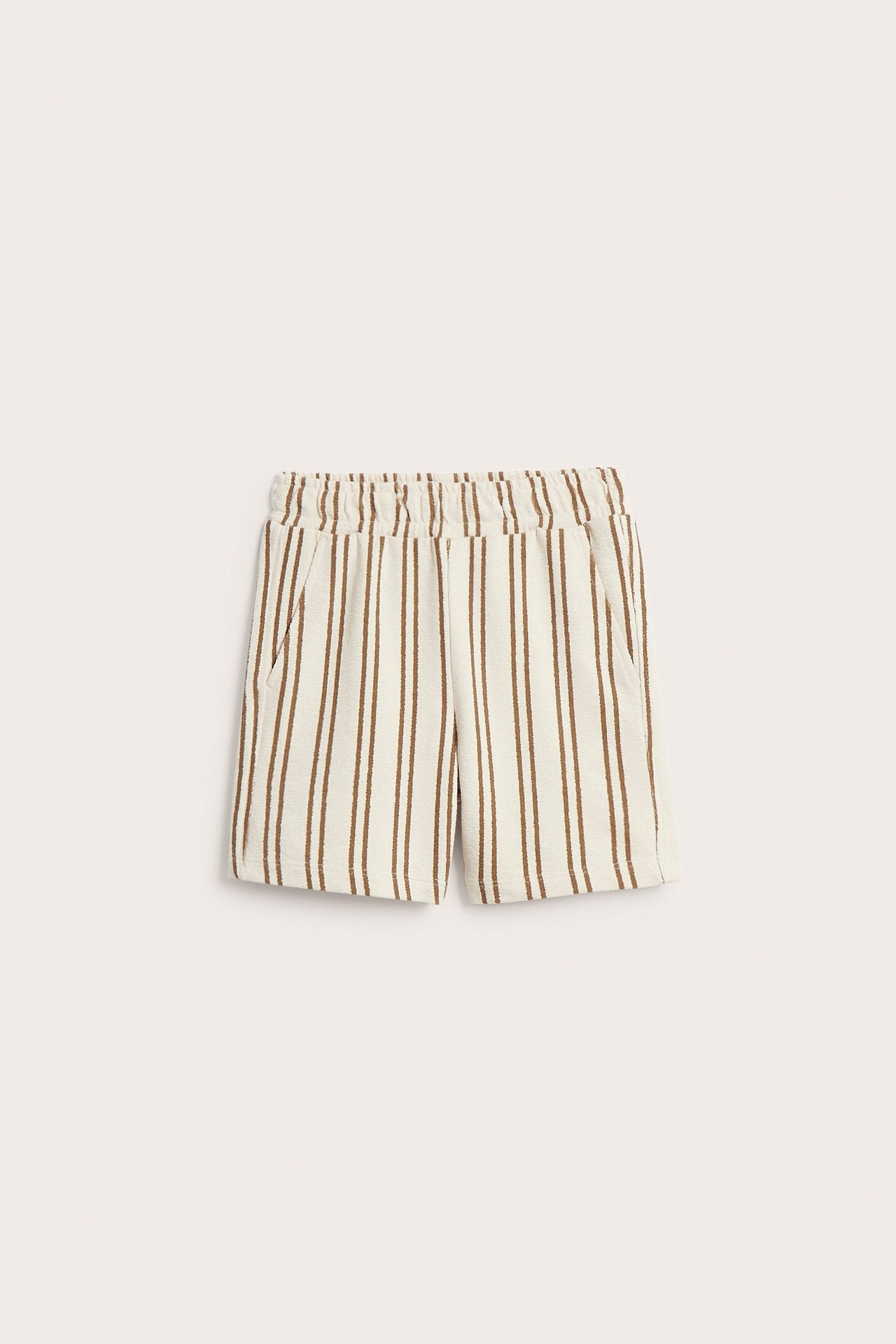 Frontvy: Barnens ljusbeige randiga bomullsjersey shorts med resår i midja och sidfickor.
