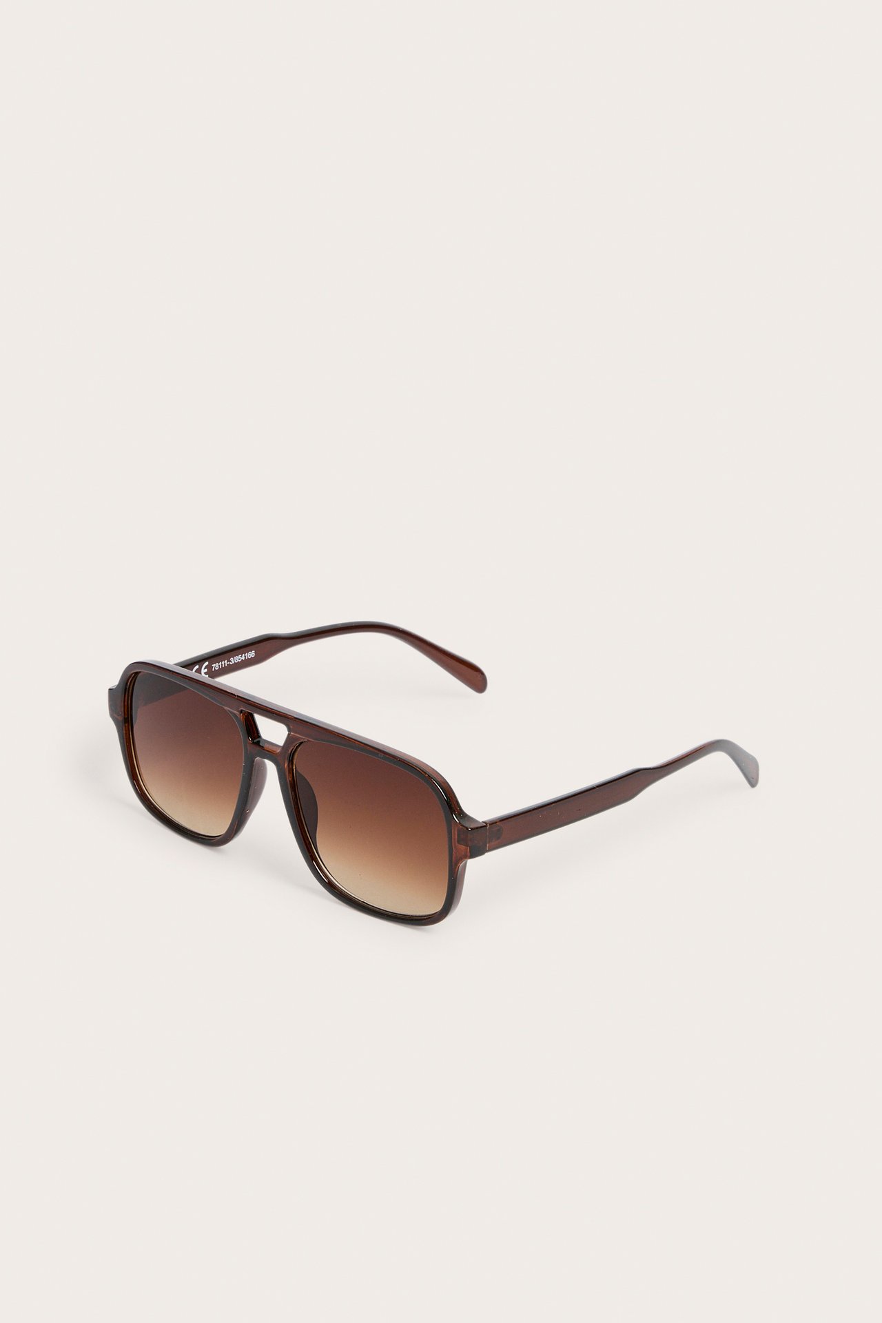 Edestä kuvatut ruskeat muoviset pilottiaurinkolasit ruskeilla liukuvärjätyillä linsseillä.