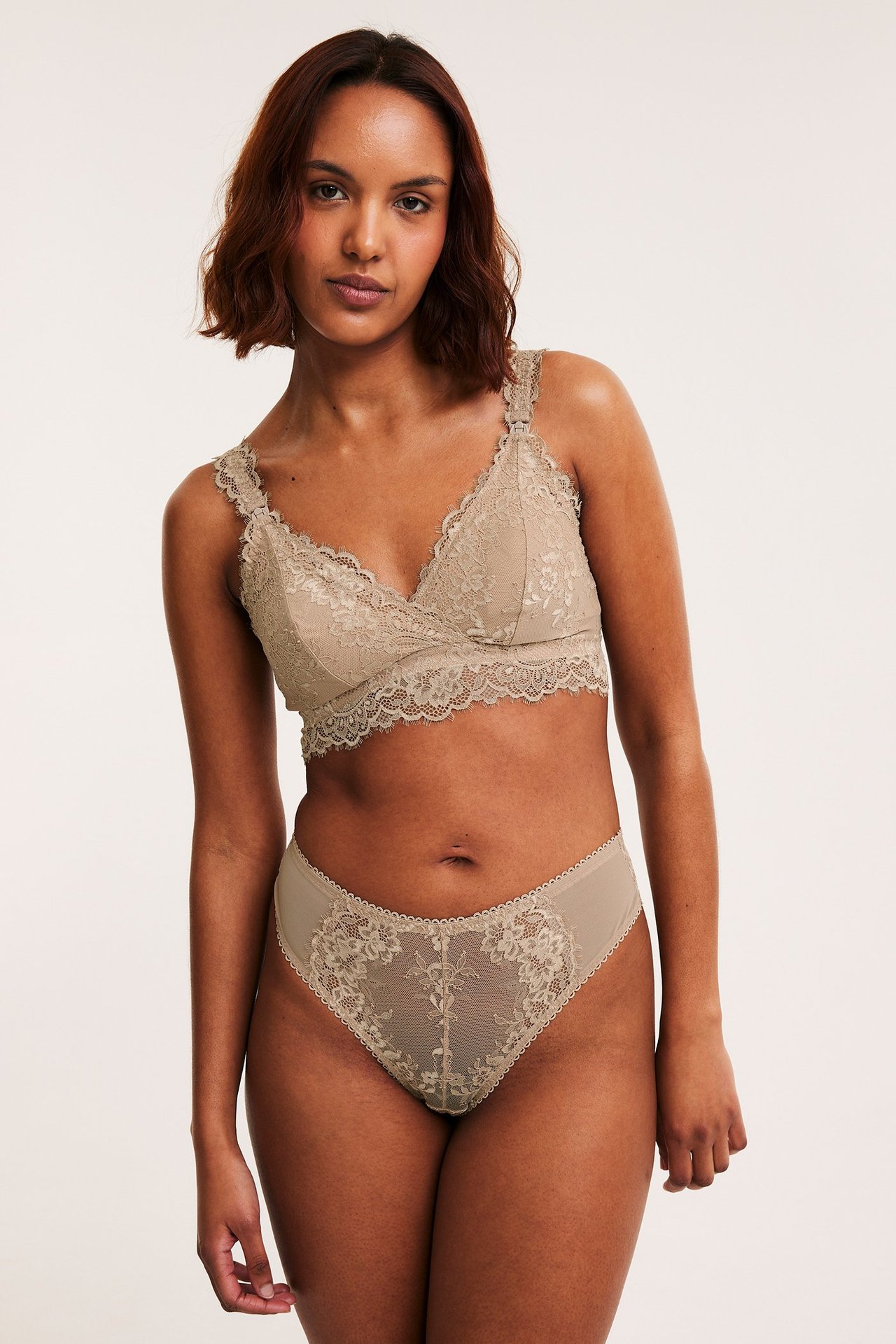 Edestä kuvattuna nainen yllään beige pitsistringit kukkakuviolla ja yhteensopivat pitsirintaliivit.