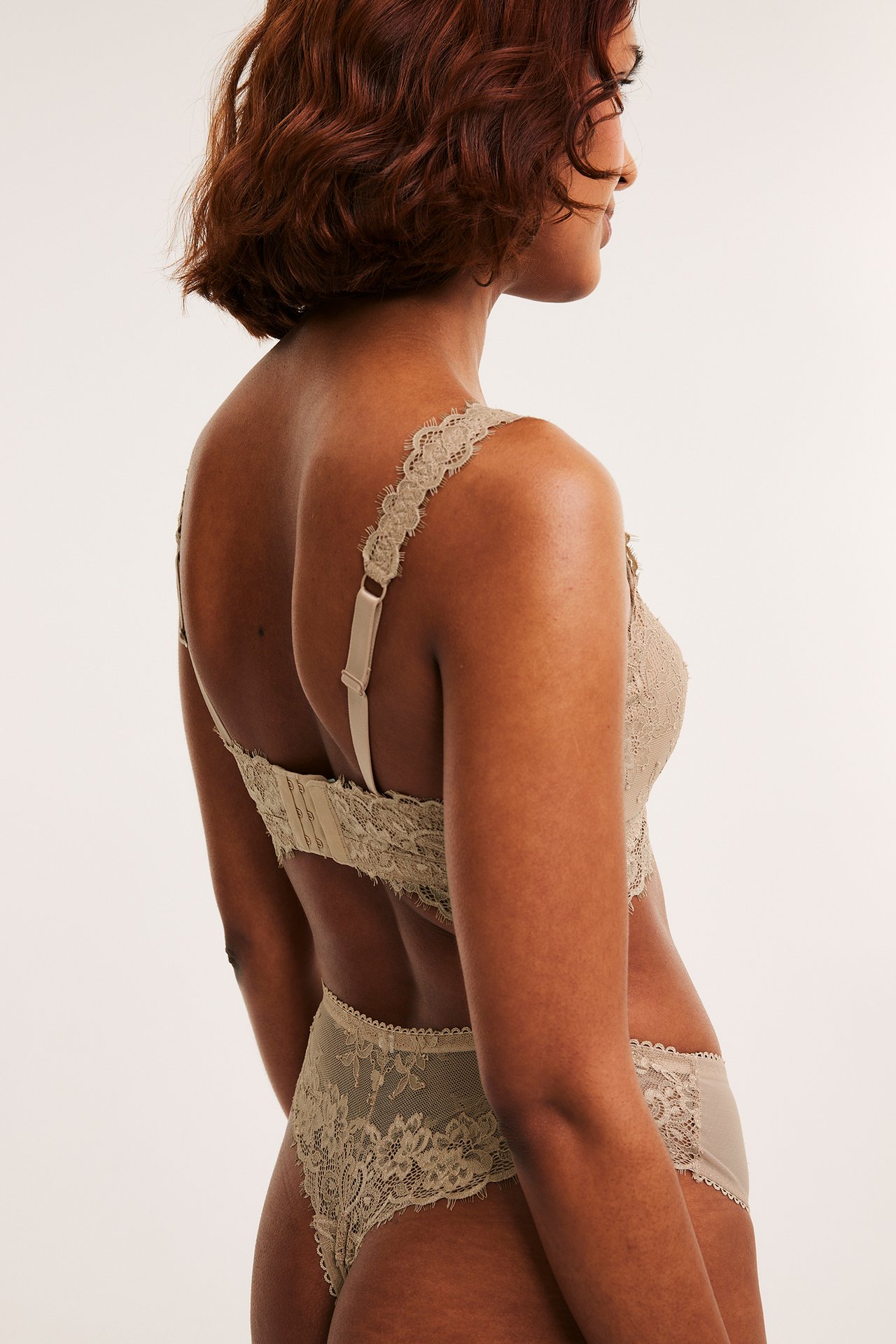 Naisen takaapäin-sivukuva vaaleanruskeissa pitsistringeissä ja yhteensopivissa pitsiliiveissä.