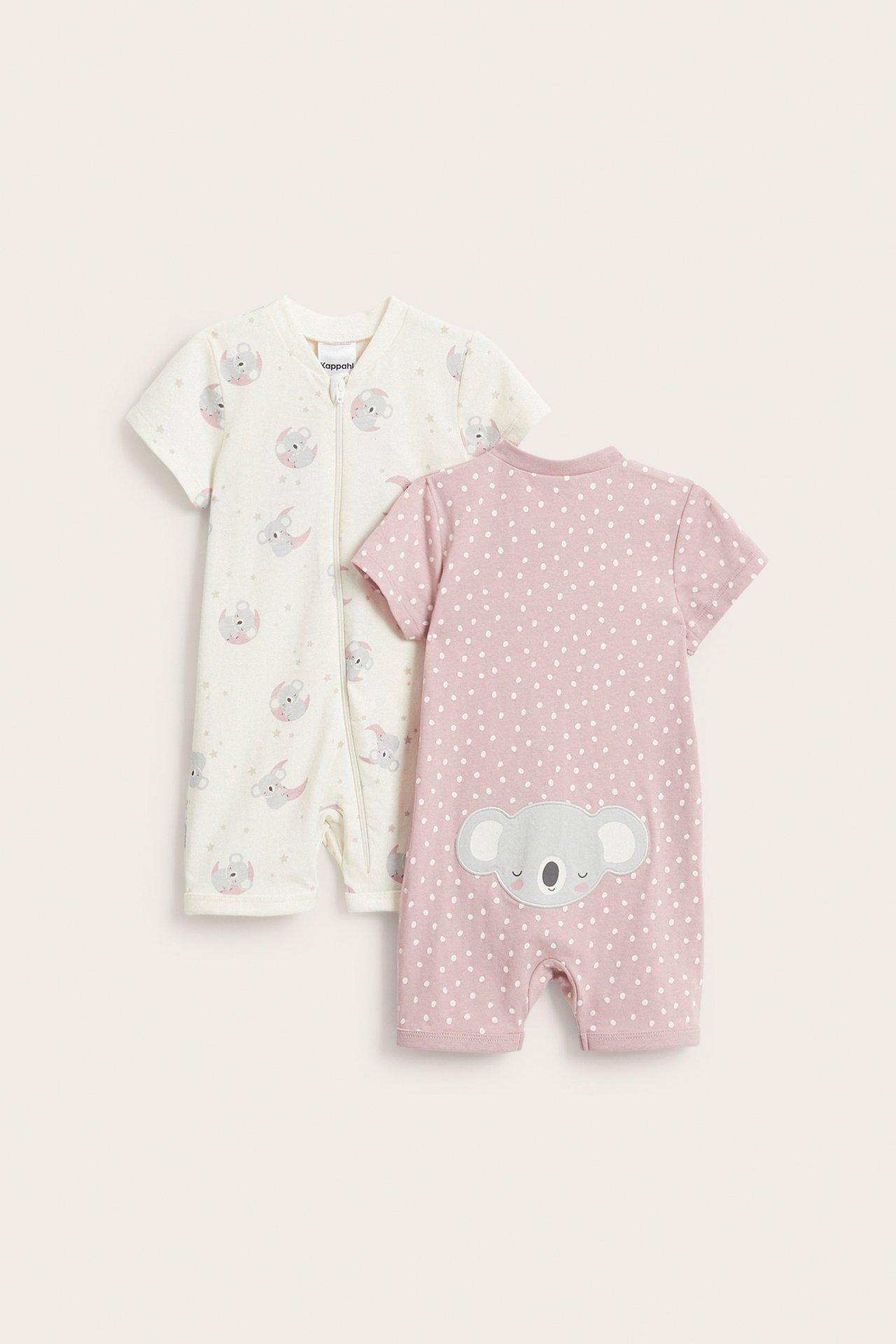 Edestä ja takaa kuvatut kaksi lyhythihaista vauvan romper-haalaria: luonnonvalkoinen koalaprintillä ja vetoketjulla, vaaleanpunainen pilkuilla ja koala-applikaatiolla.