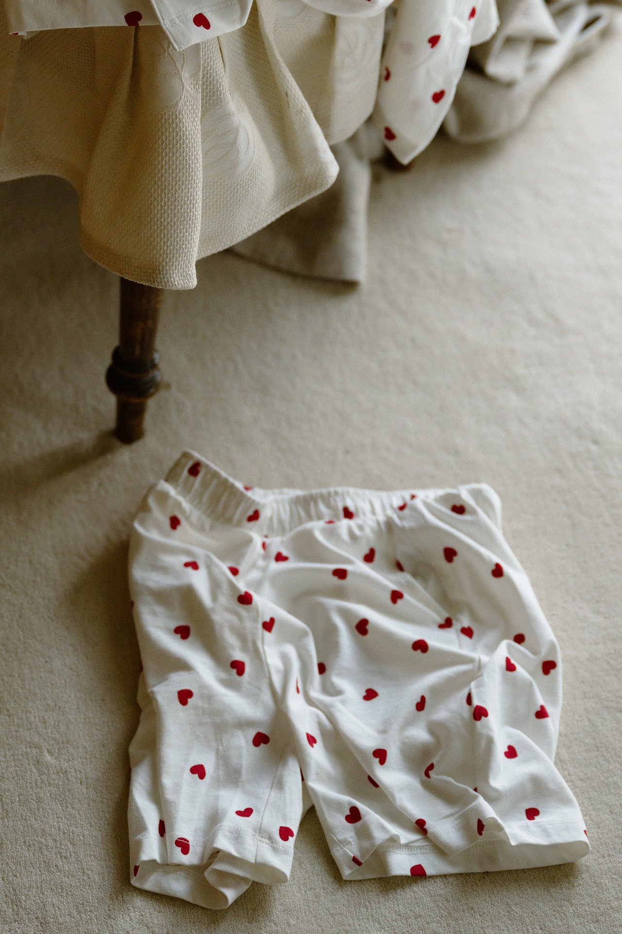 Sett ovenfra: offwhite pysjamas shorts for herre med røde hjerter og elastisk linning.