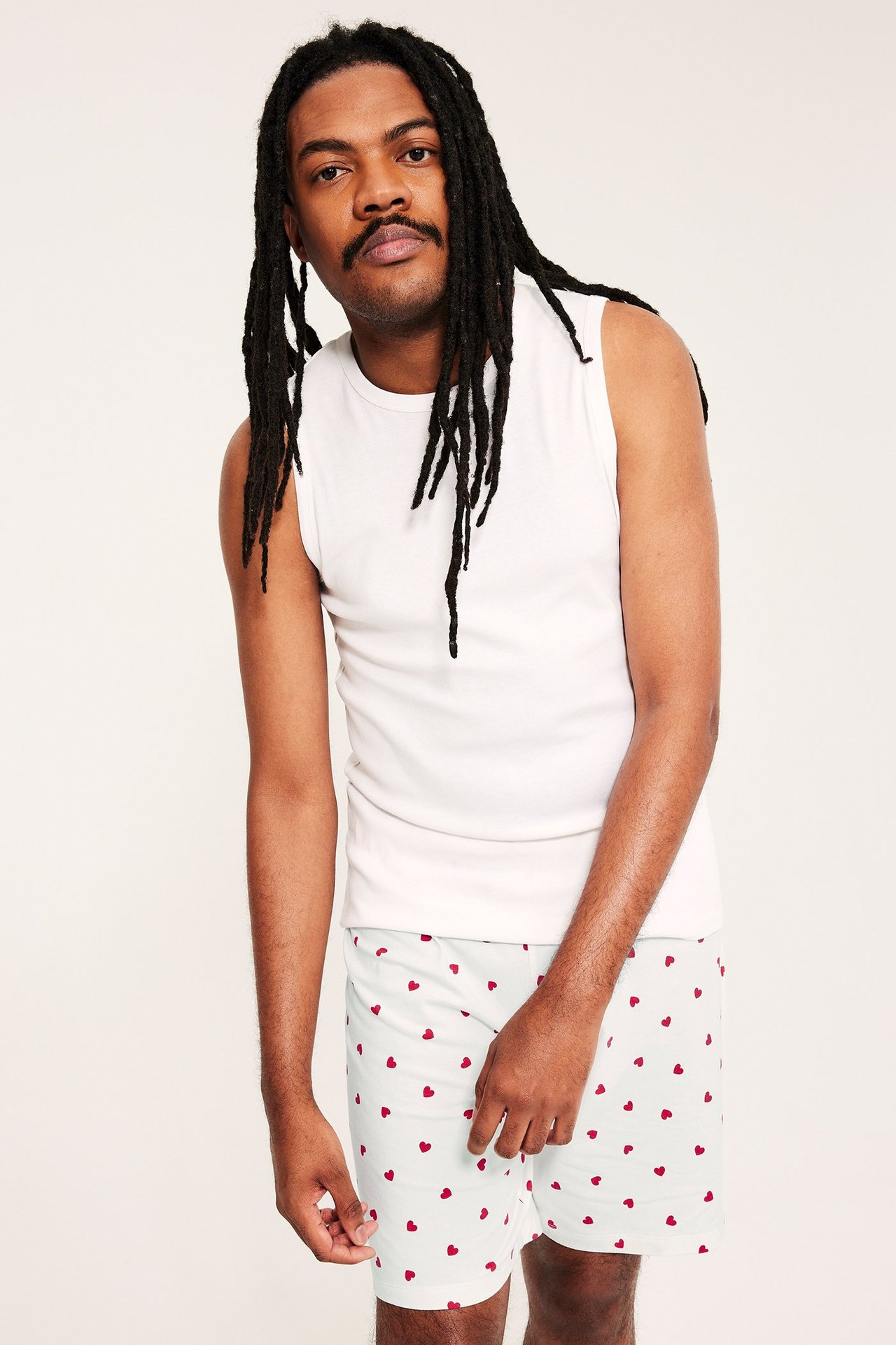 Widok z przodu: mężczyzna w jasnozielonych szortach piżamowych w serca i białym podkoszulku.