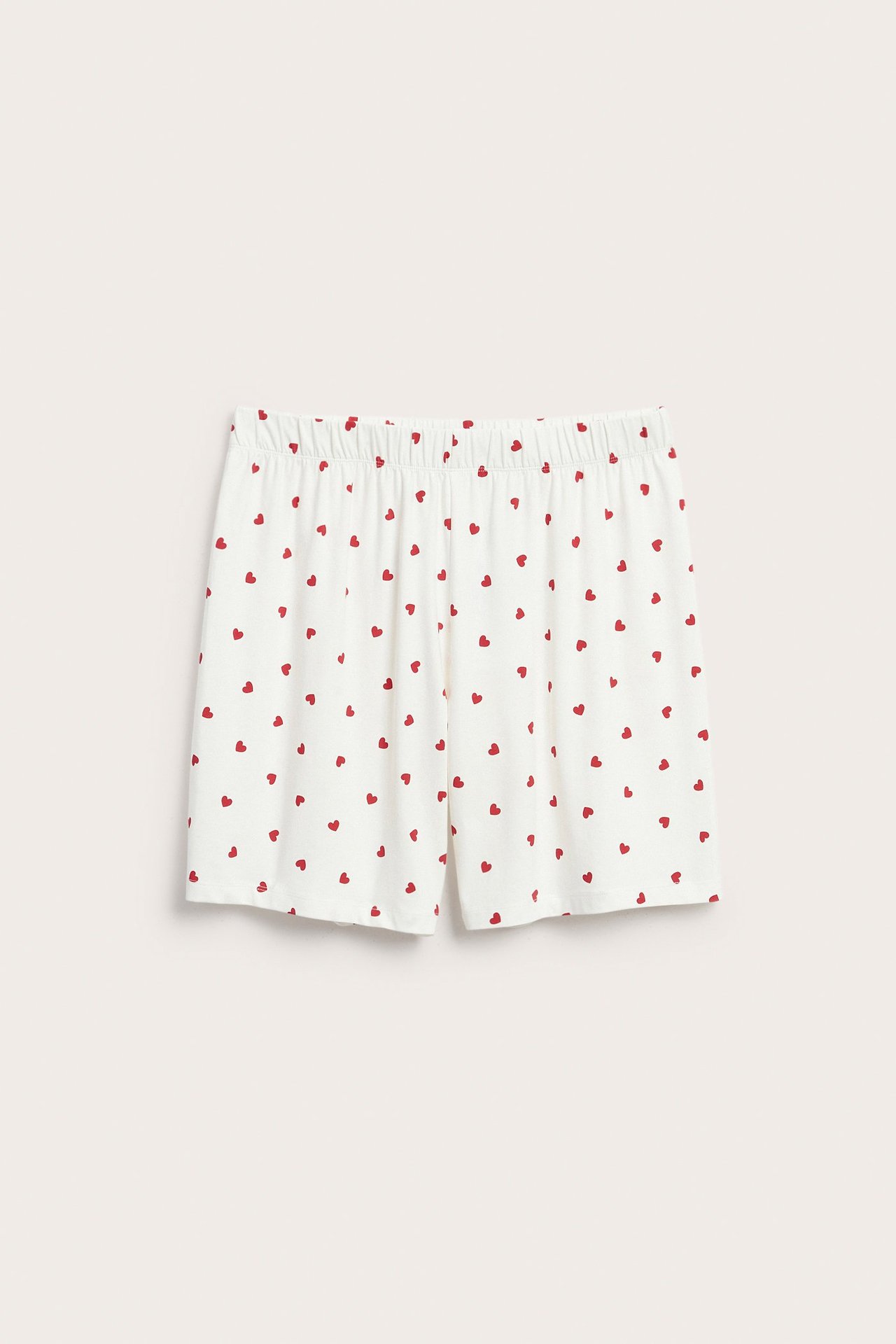 Frontbilde av offwhite pyjamasshorts med rødt hjertemønster og elastisk midje.
