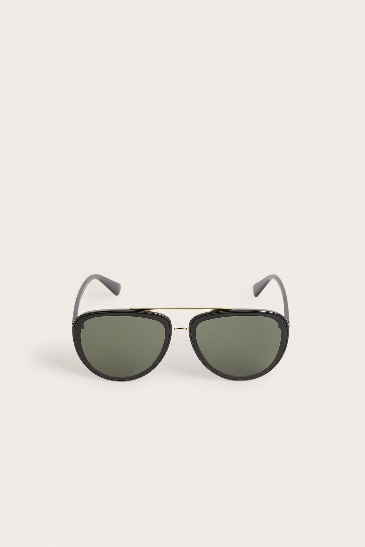Edestäpäin mustat pilottiaurinkolasit tummilla linsseillä ja kullanvärisellä metallisillalla.