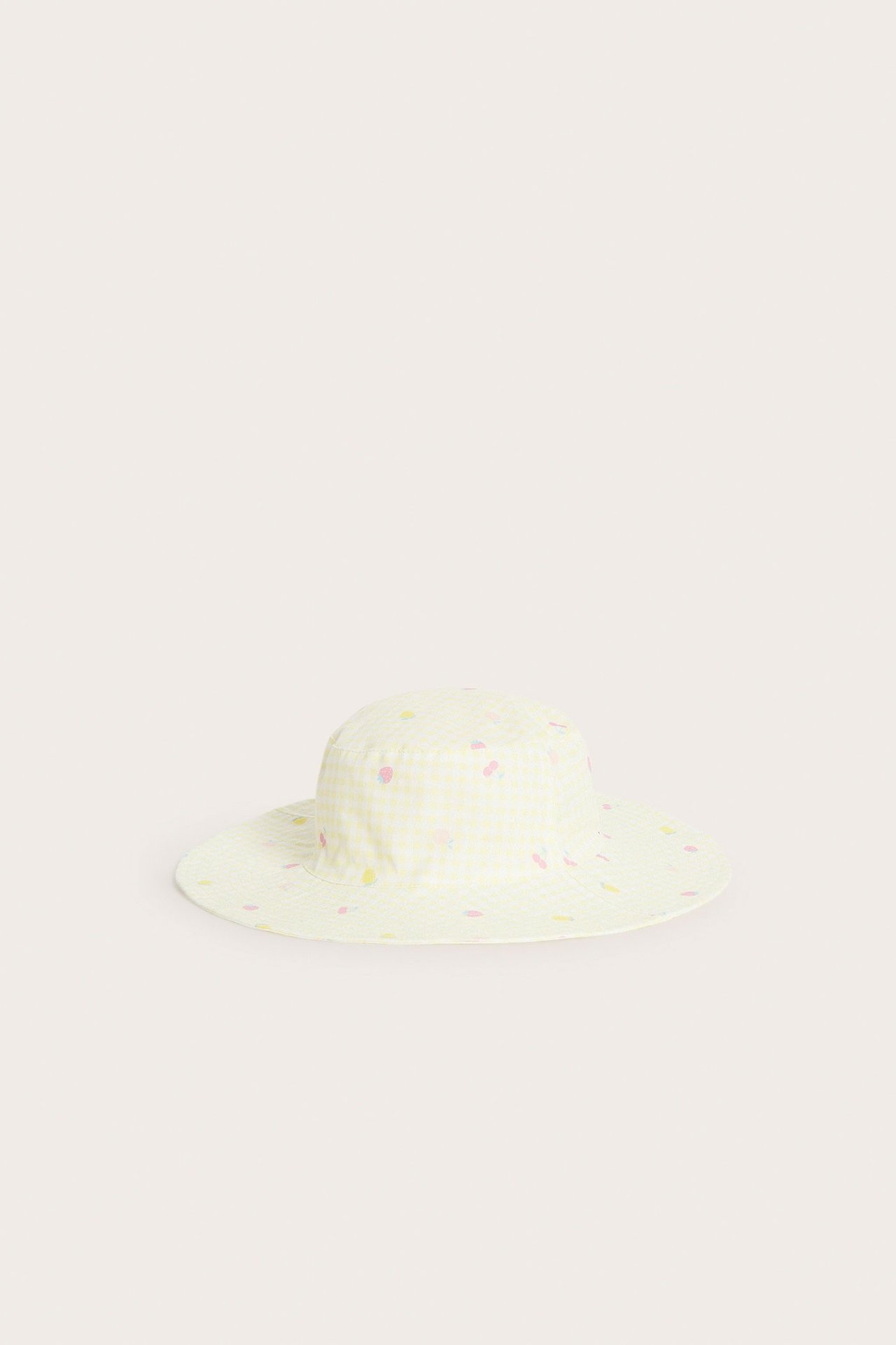 Widok z przodu dziecięcego, jasnożółtego kapelusza przeciwsłonecznego w kratkę, z bawełnianego diagonalu z kolorowym nadrukiem owoców i warzyw.