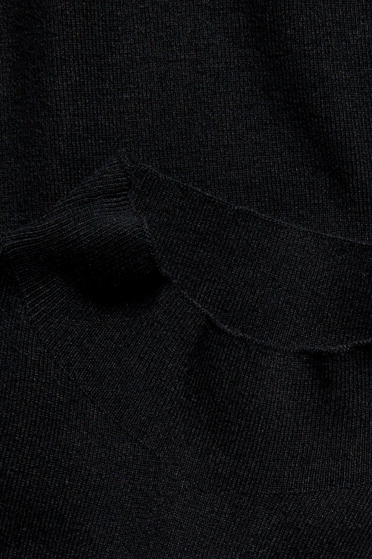 Zbliżenie czarnej dzianinowej kamizelki z kołnierzem, ukazujące prążkowaną teksturę materiału.