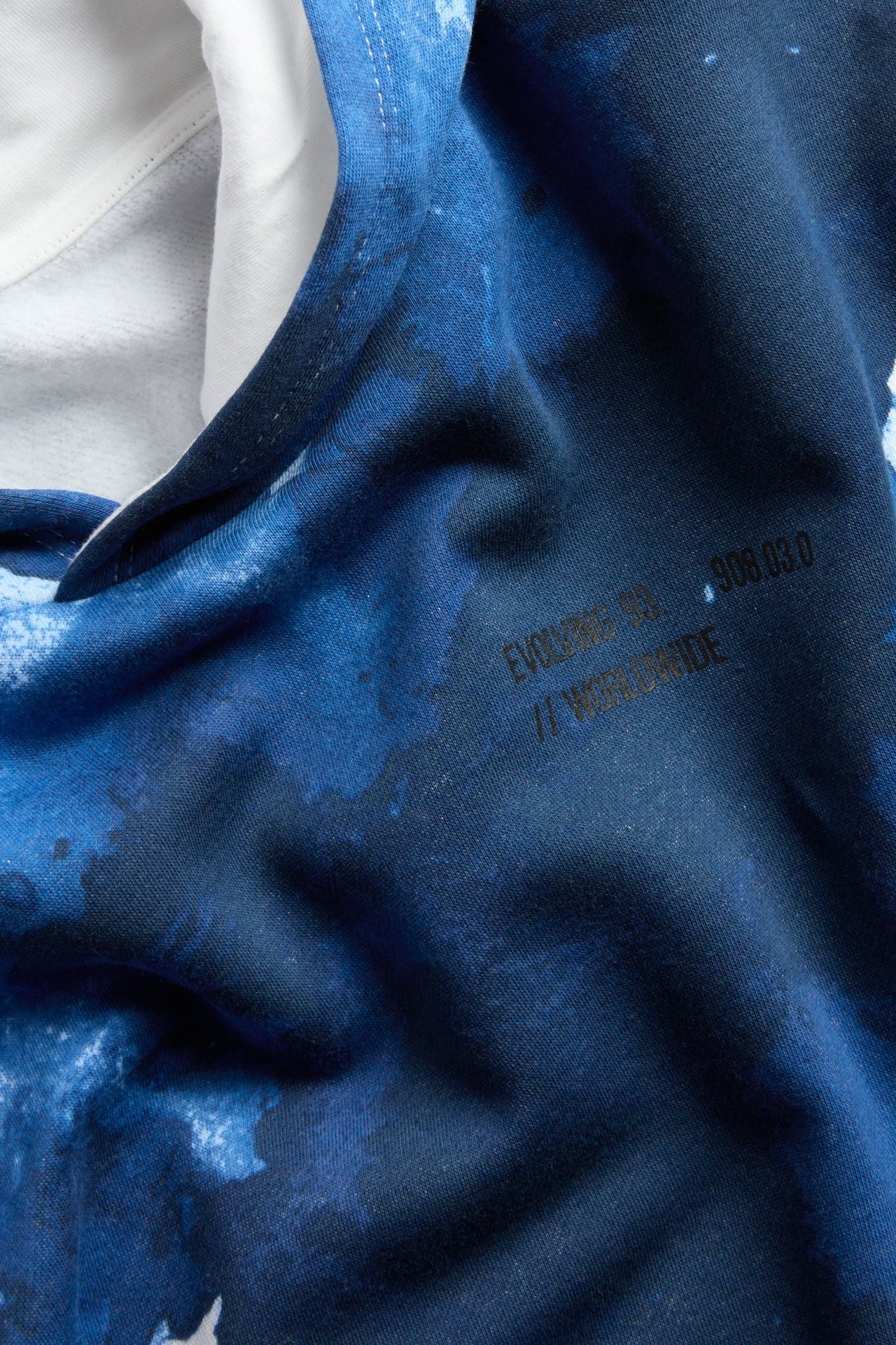 Zbliżenie na dziecięcą wzorzystą bluzę z kapturem, granatową z abstrakcyjnym jasnoniebieskim nadrukiem i off-white podszewką.