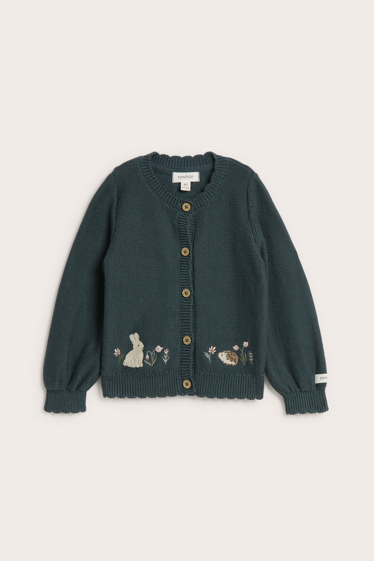 Forfra, en mørkegrønn strikket barnekardigan med brodert kanin og pinnsvin.