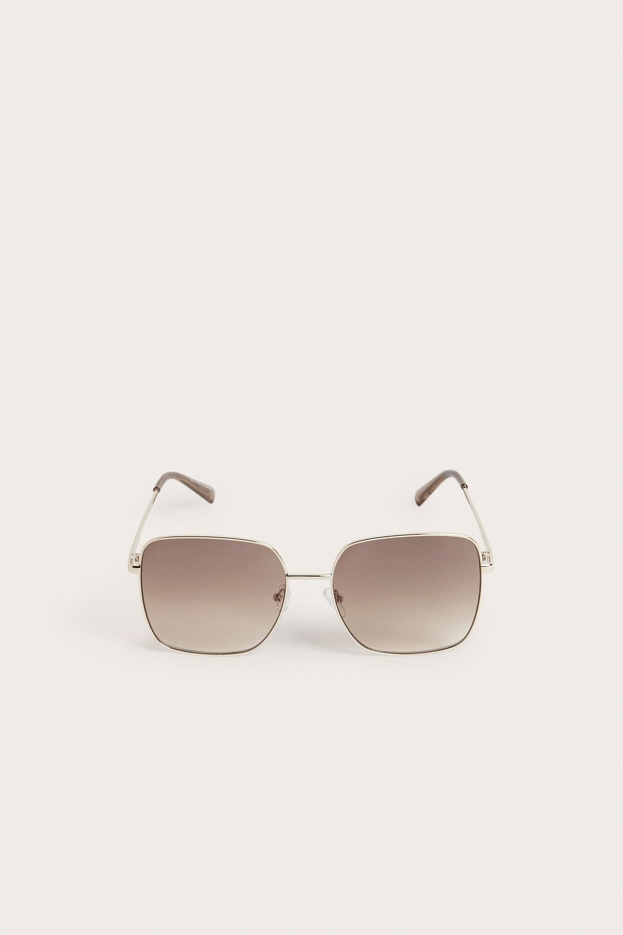 Edestä kuvatut kultaiset metallikehyksiset aurinkolasit, joissa neliömäiset ruskeat liukuvärilasit.