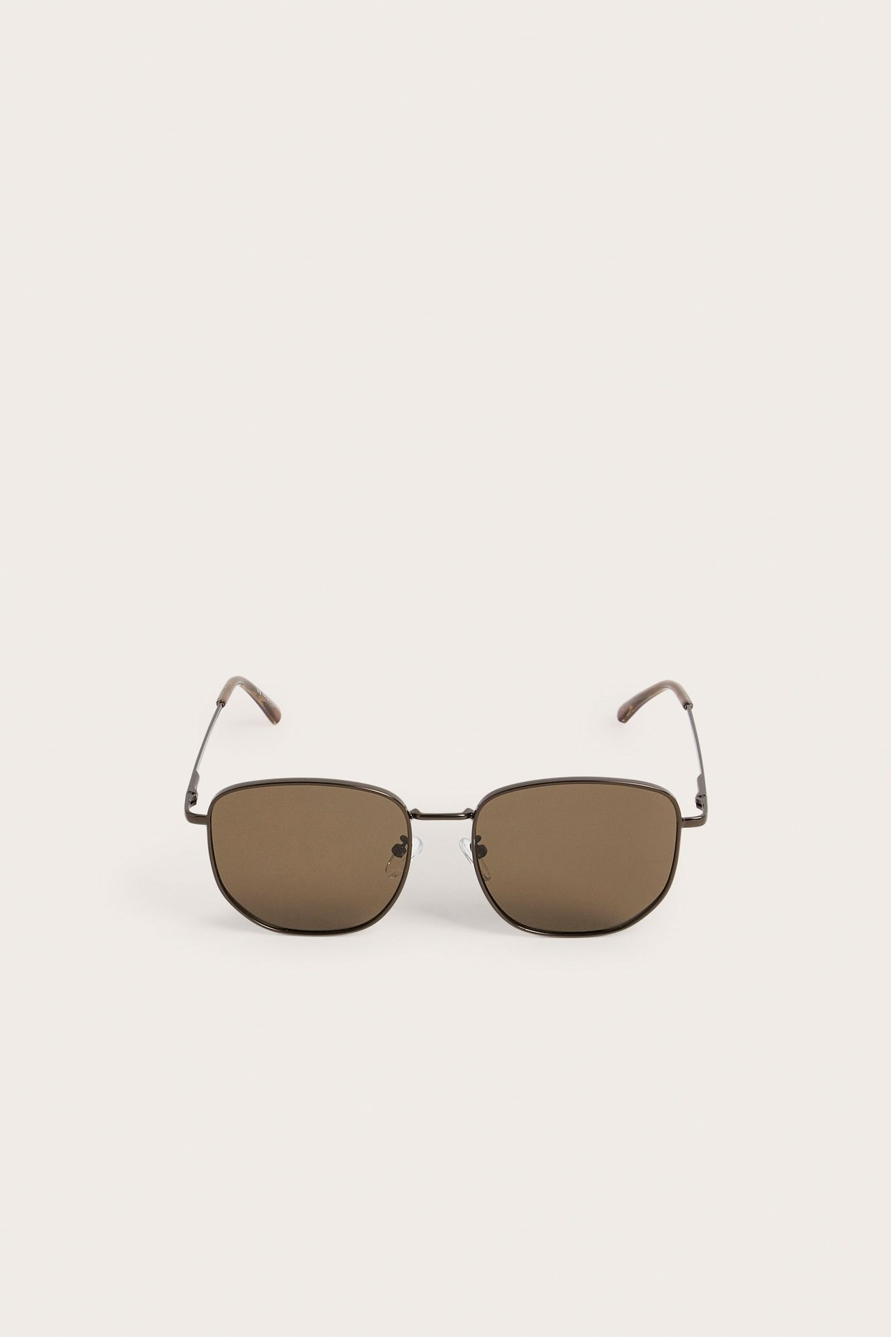 Etunäkymä yksivärisistä mustista metallikehyksisistä aurinkolaseista, joissa on ruskeat linssit.